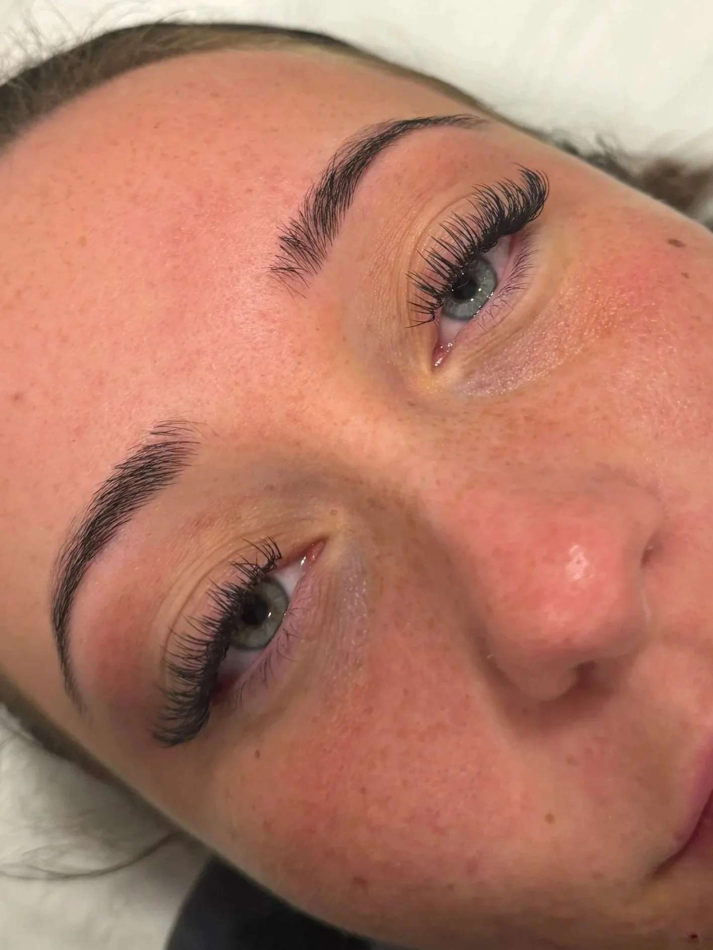 Close-up of a person's face focusing on the eyes, eyebrows, and surrounding skin with freckles.