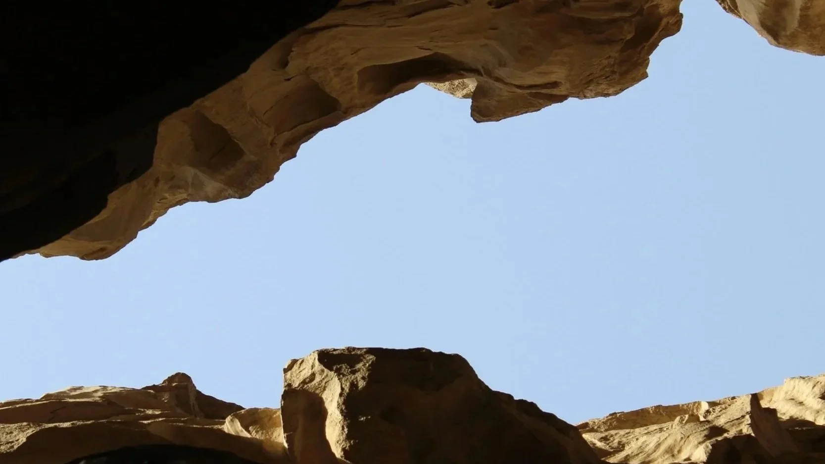 View of the sky seen from within a canyon with sandstone walls.