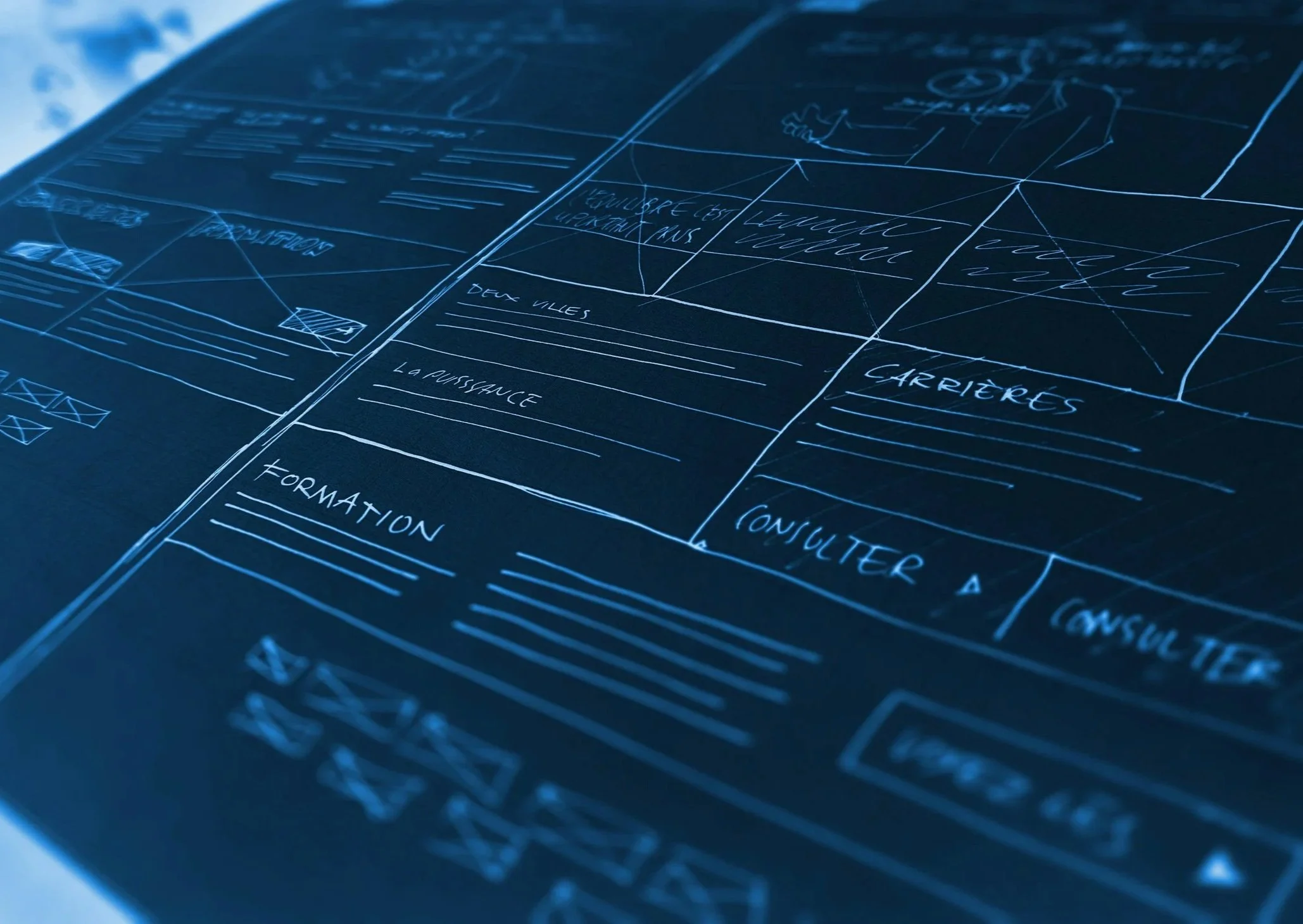 Blueprint of a website layout with sections labeled in French, including 'Formations,' 'Deux Vues,' 'La Puissance,' and 'Carrières,' drawn with white lines on a dark background.