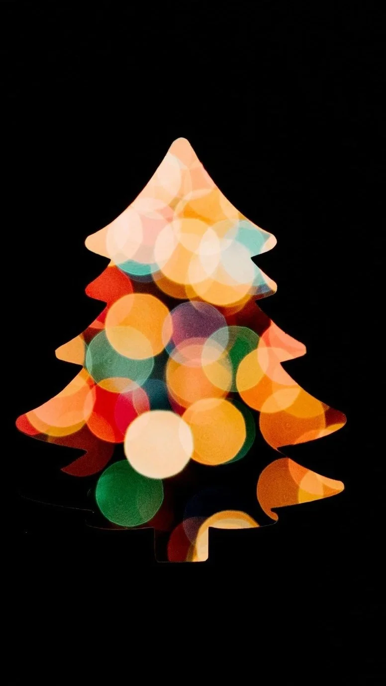 Blurred Christmas tree shape with colorful lights against a black background.