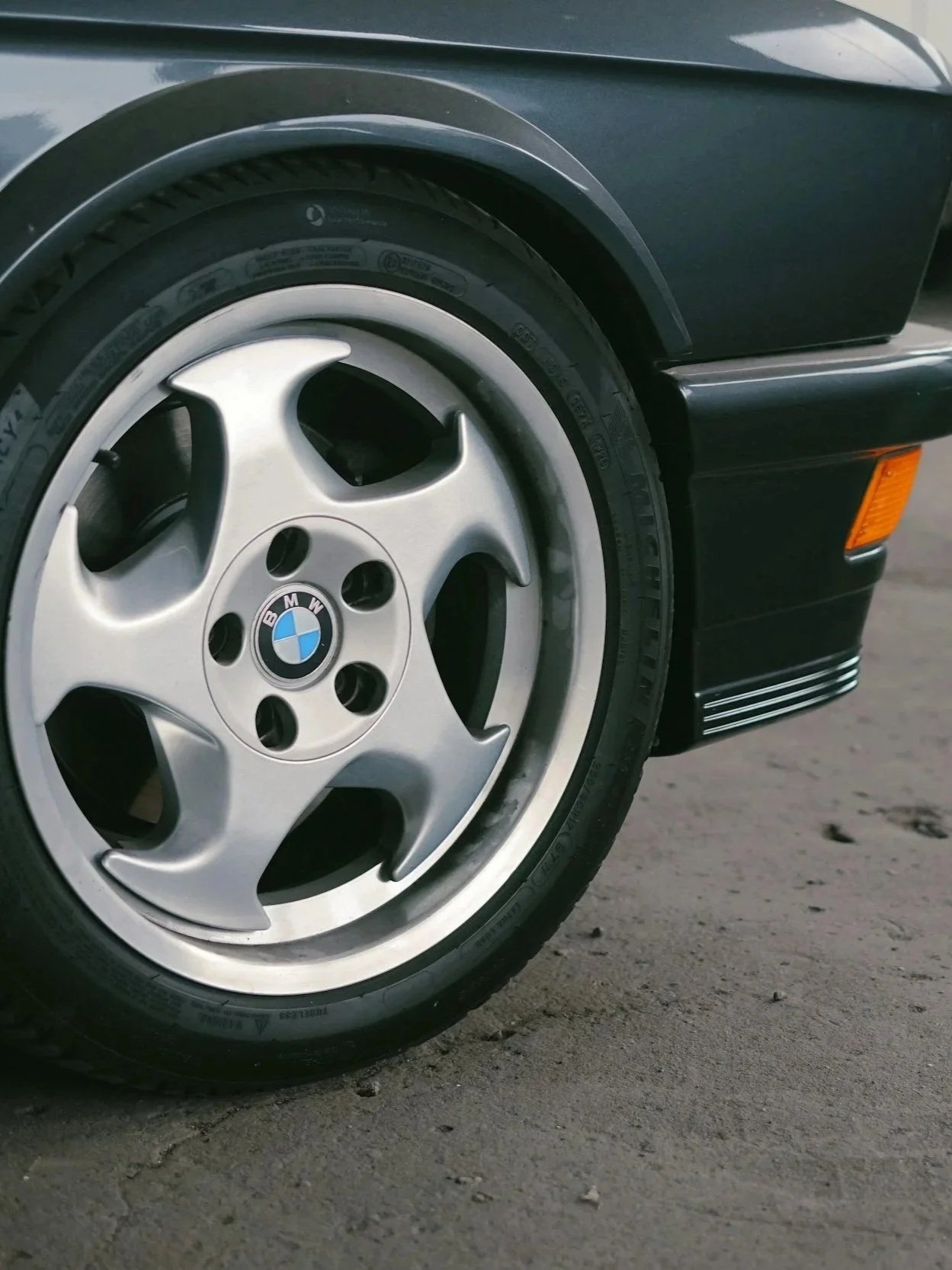 Close-up of a black BMW car wheel and tire, with part of the black car body visible.