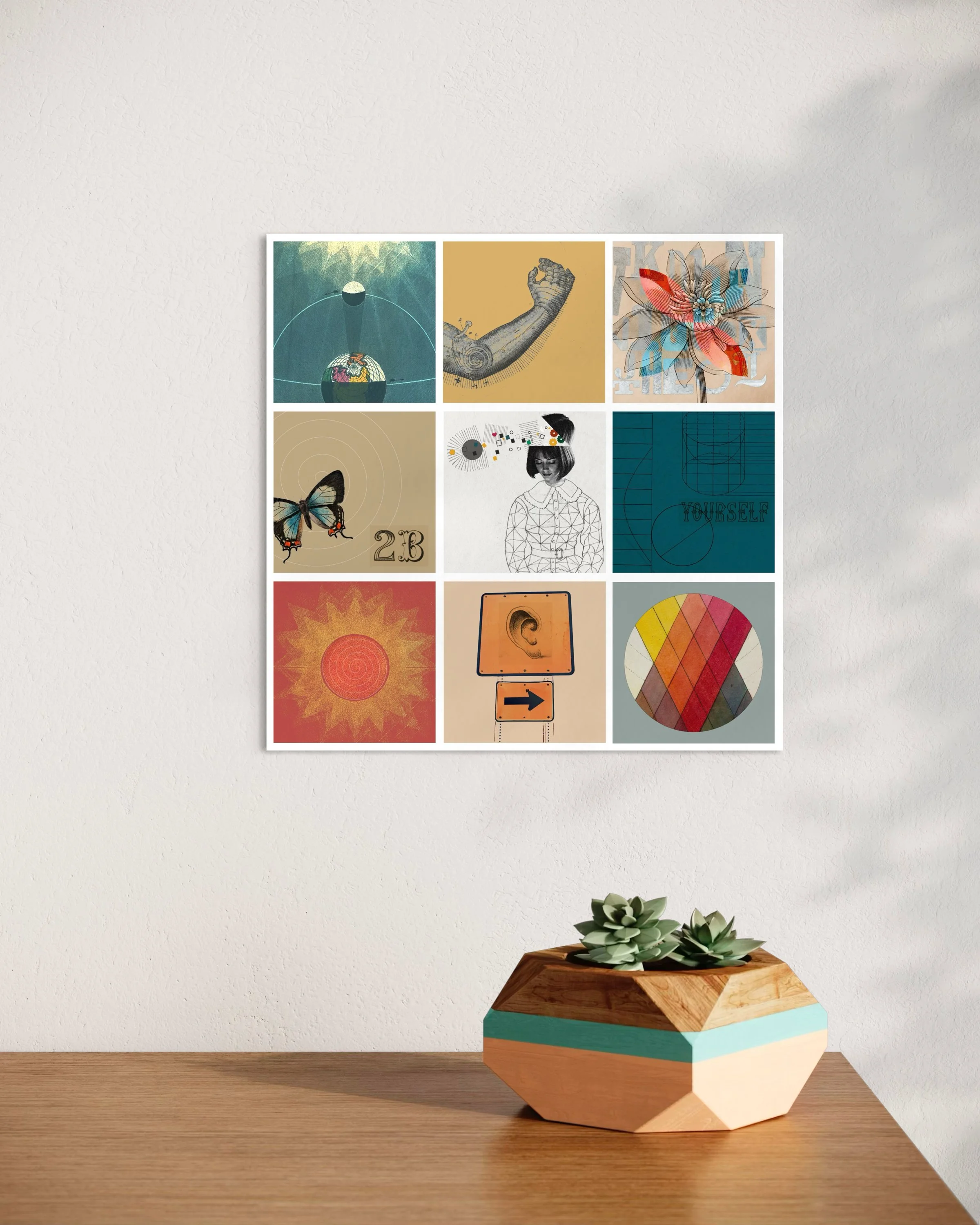Fragments collage print displayed unframed on a light wall above a wooden surface with a small geometric planter containing succulents in a bright modern interior.