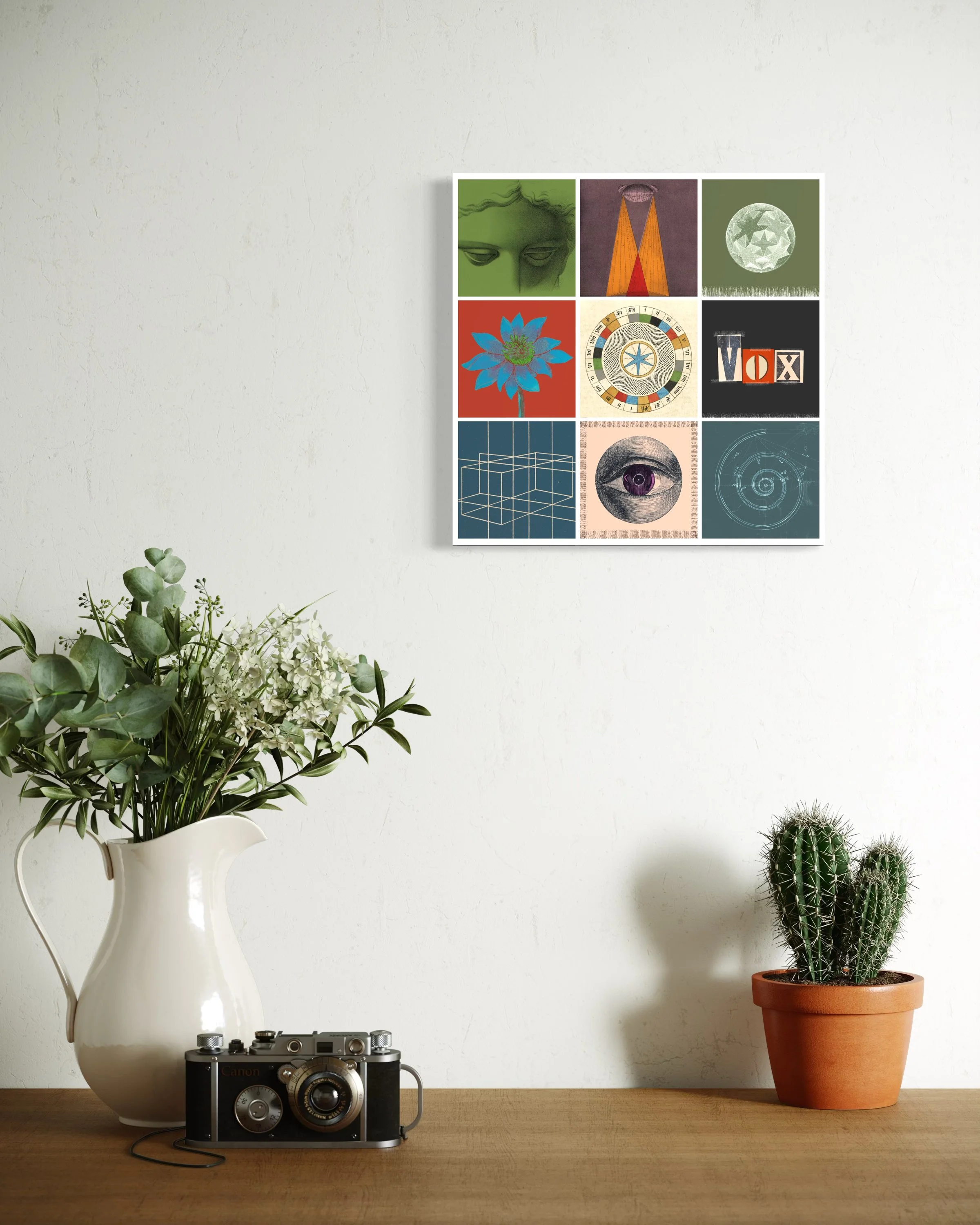 Alchemy fine-art print displayed on a wall above a wooden surface with a vintage camera, a white jug of flowers and a potted cactus
