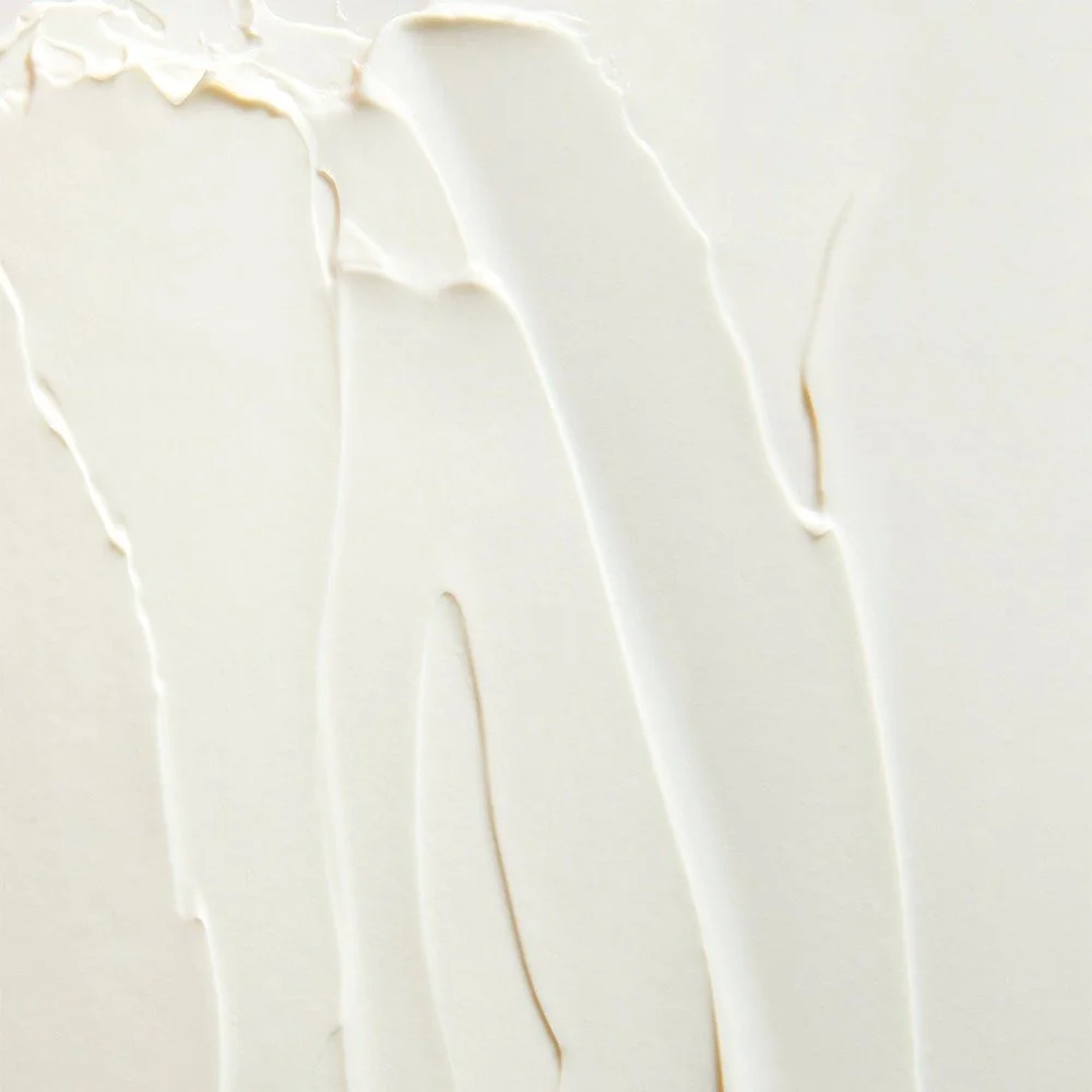 Close-up of a smooth, white surface with streaks of a thick, creamy substance, possibly lotion or cream.