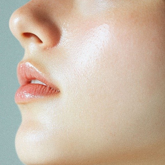 Close-up of a woman's lips, nose, and cheek with natural makeup and dewy skin by RIMAN.