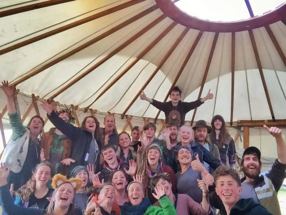 A large group of smiling kids and adults inside a circular tent with a domed roof, celebrating and posing for a photo.