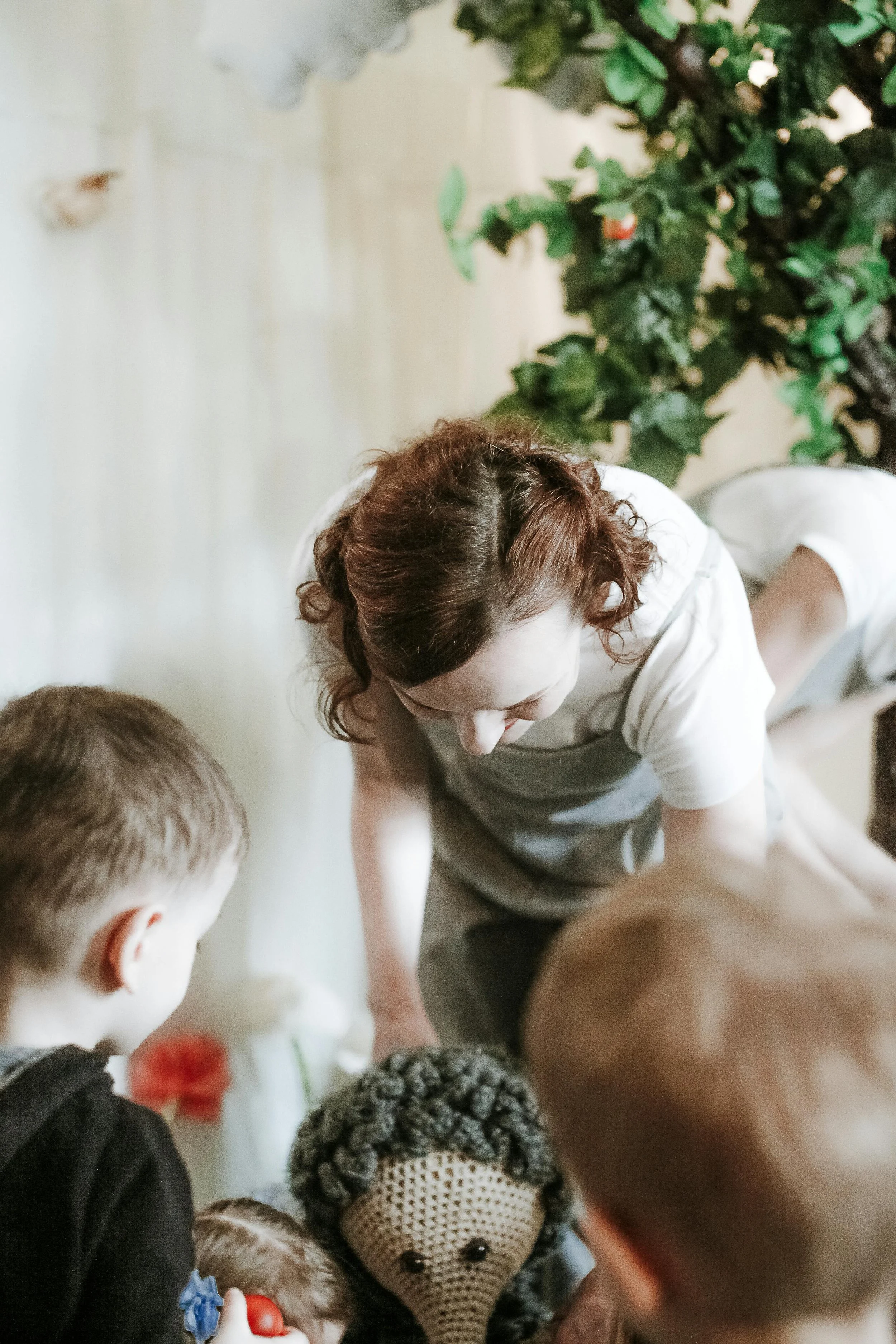 Un couple de jeunes mariés en tenue traditionnelle malaise, assis devant un fond floral entièrement blanc, faisant des gestes espiègles avec leurs mains.