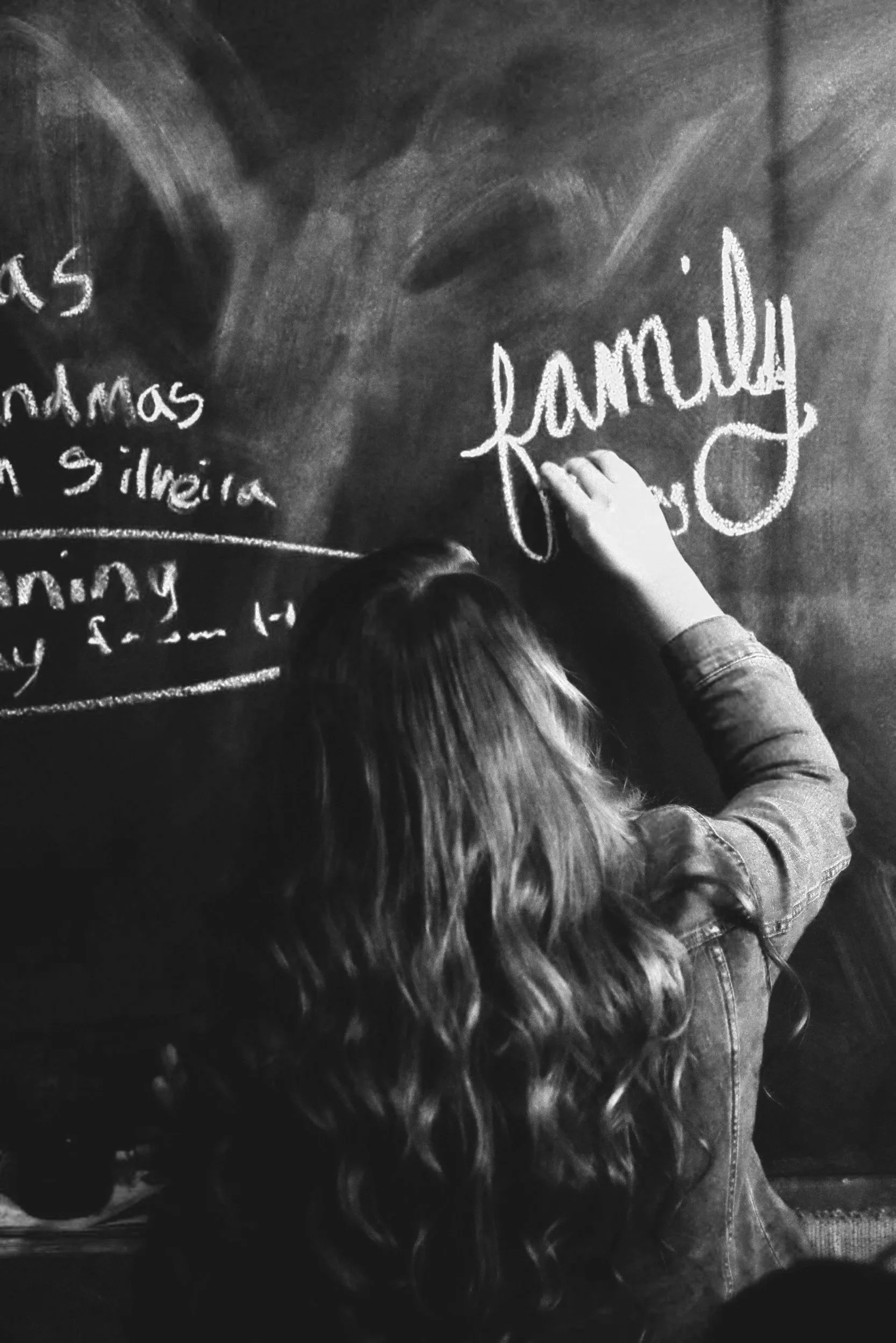 Person writing on a chalkboard with the word 'famous' in white chalk.