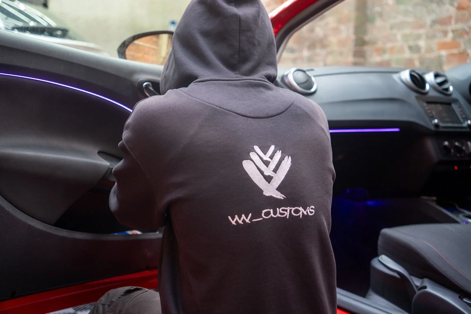 VVV Customs technician fitting purple ambient LED lighting inside a car interior, working on the dashboard and door trim.