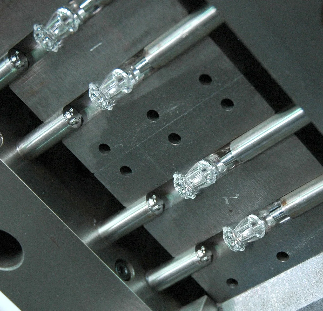 Close-up of a mechanical device with glass components and metal rods, likely part of a scientific or industrial apparatus.