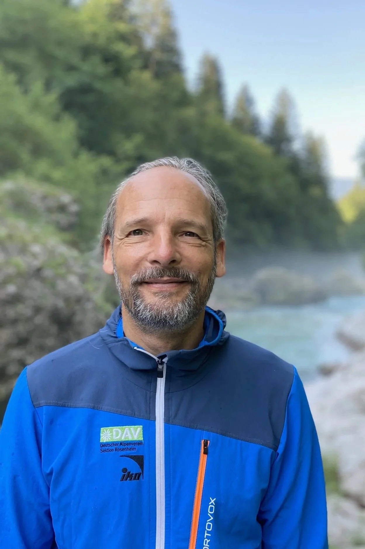 Porträt von Daniel Huthmacher, Coach und Supervisor, vor einer Berglandschaft mit Fluss