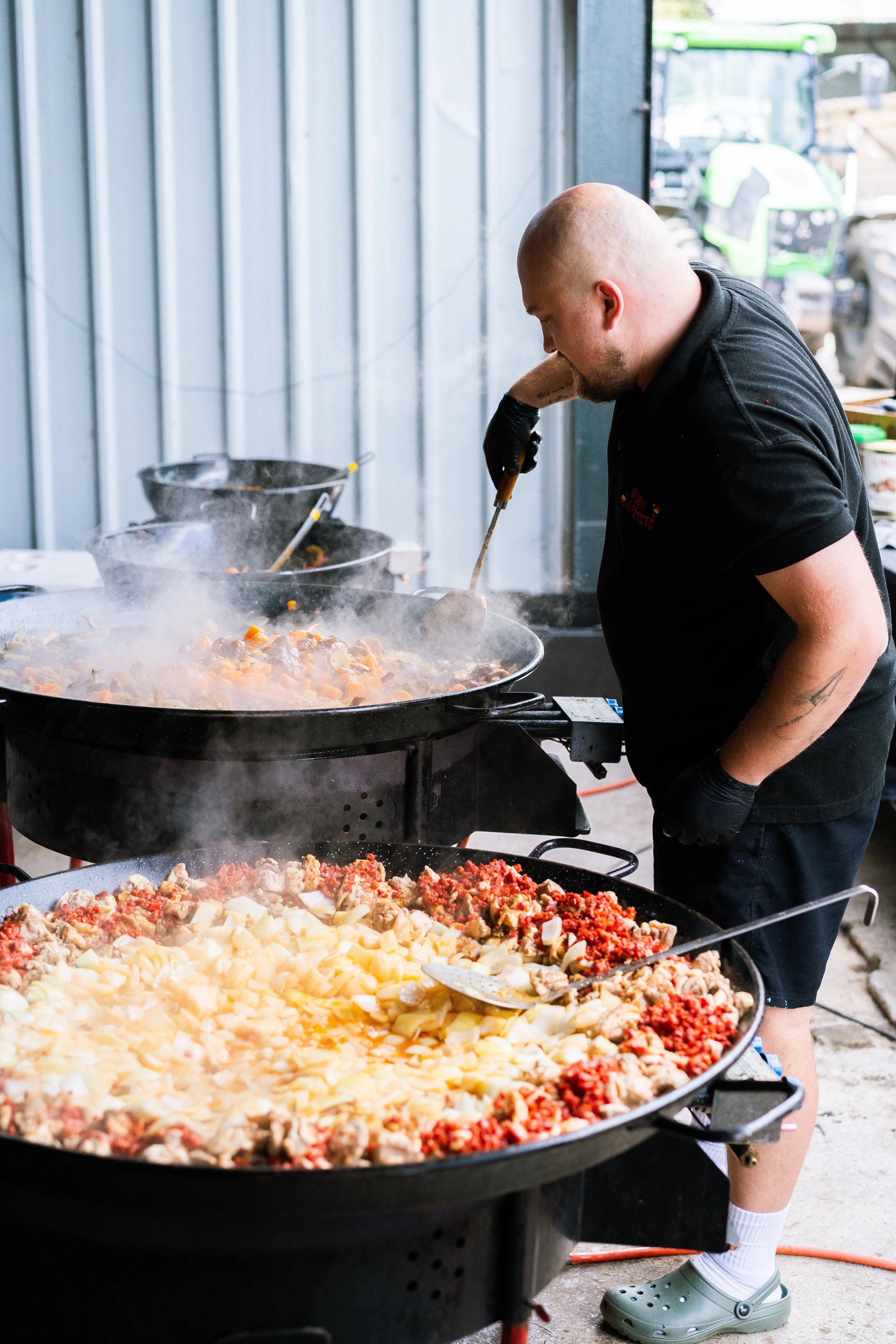 Man cooking large amounts of food, possibly chili, in an industrial kitchen.