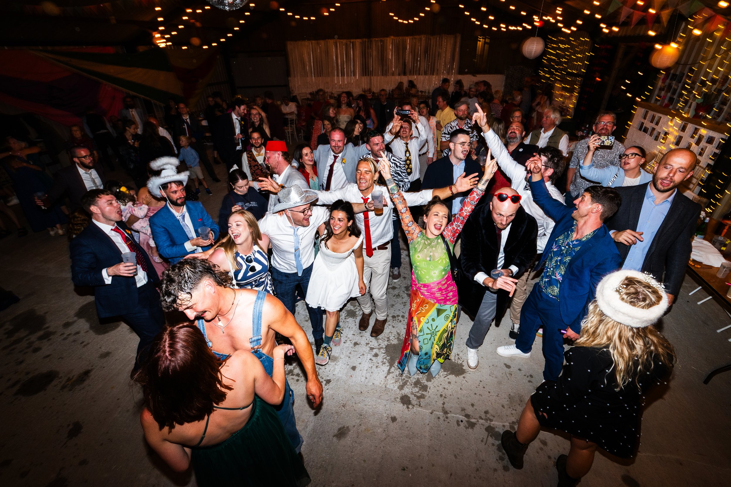 People dancing and celebrating at a party with string lights and decorations.