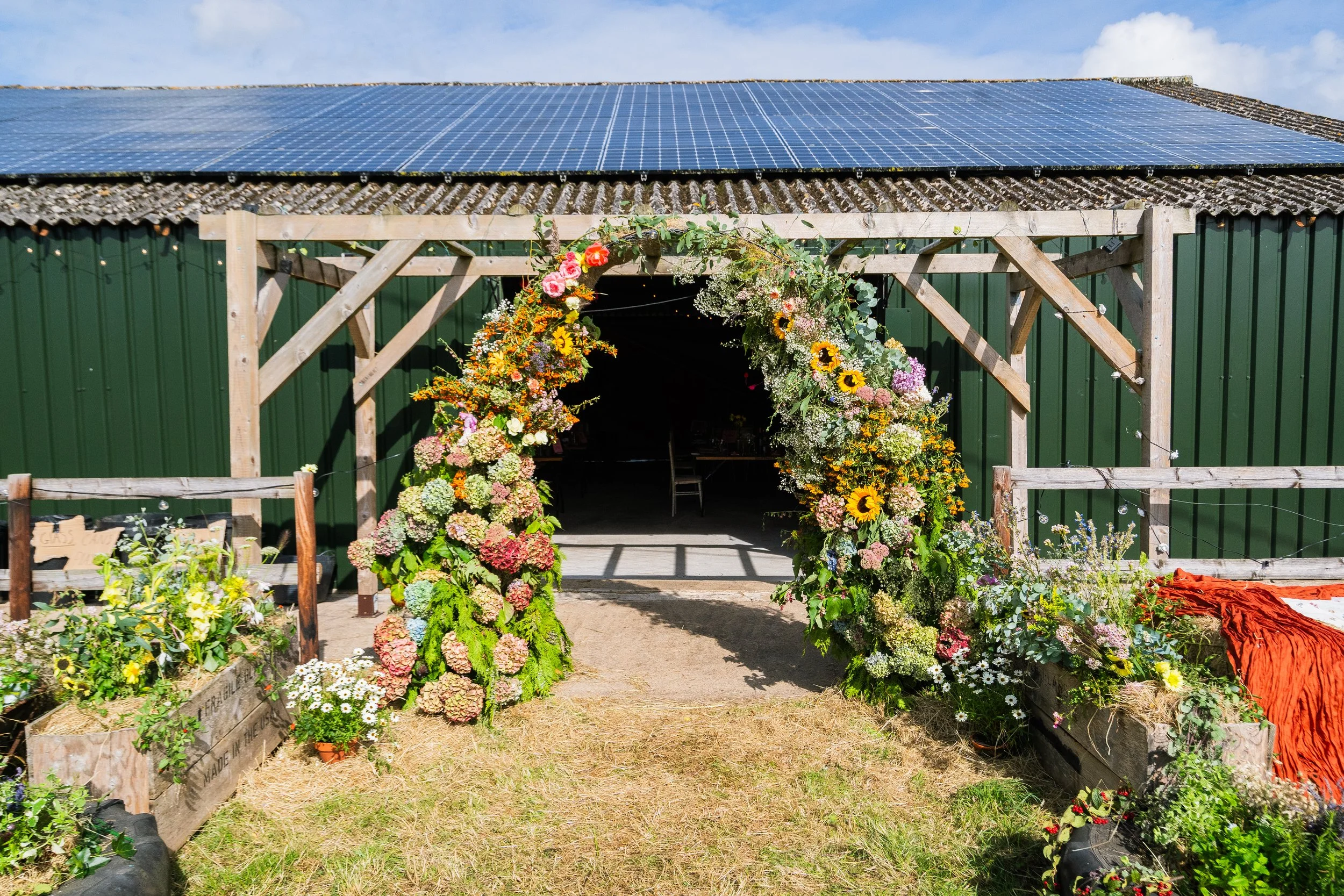 Colorful flower arch in front of a barn with solar panels on the roof