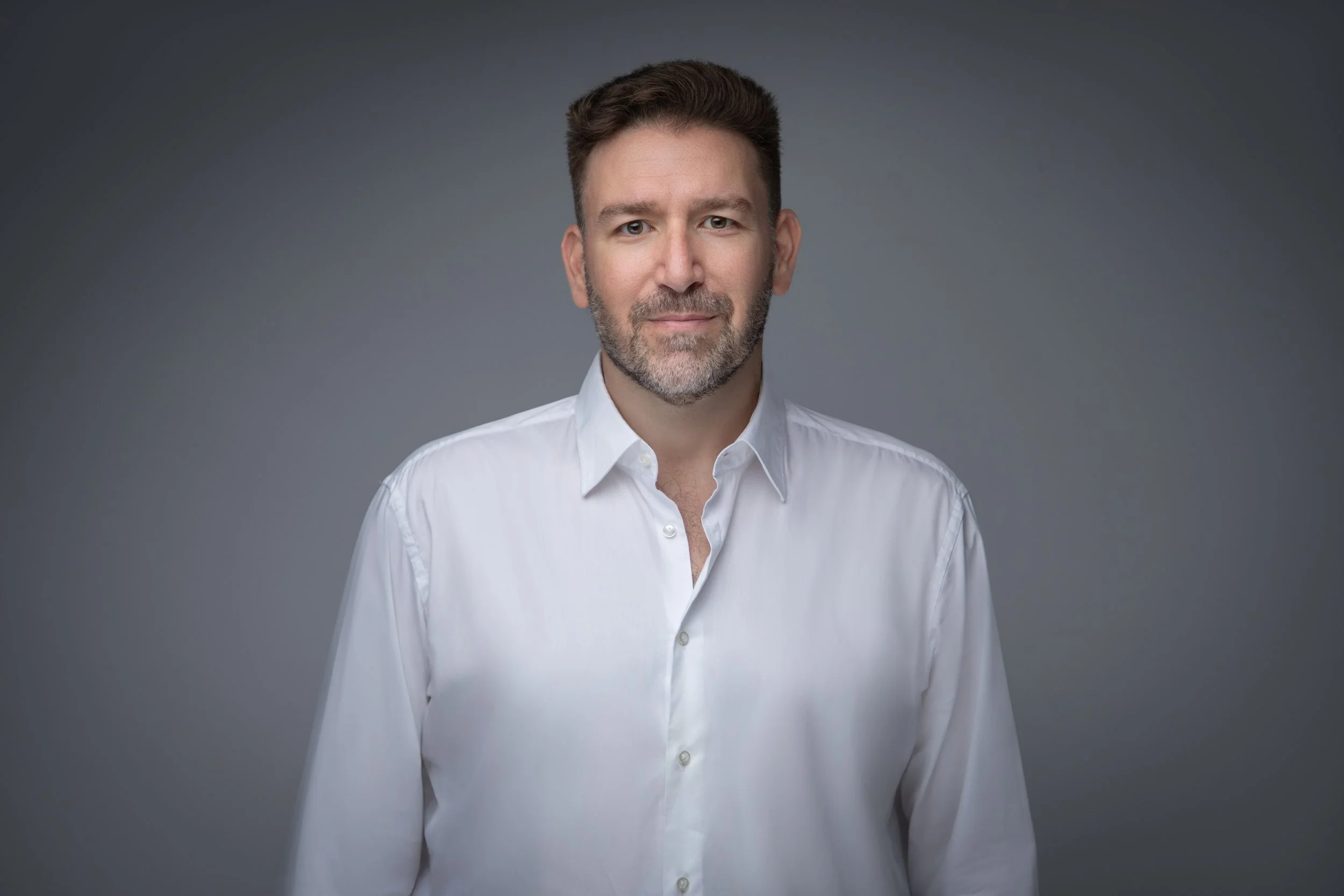 Nadim Samara: a man in a white shirt and white collared shirt standing with arms by his side