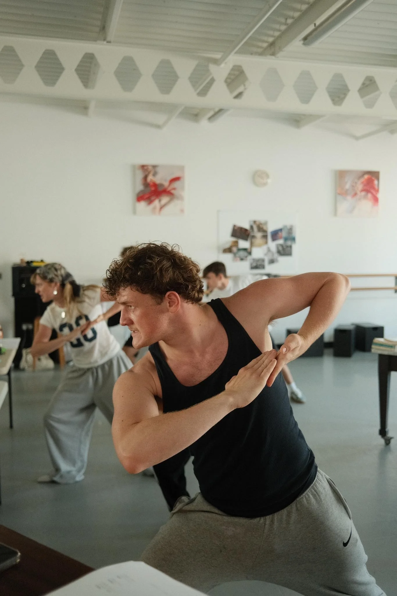 People practicing yoga in a room with white walls, paintings, and photos on the wall.
