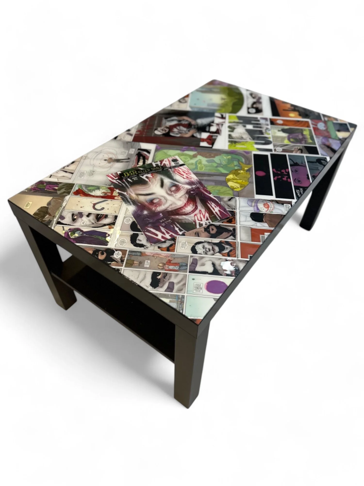 A black coffee table decorated with various comic book pages and illustrations, some overlapping and arranged in a collage style.