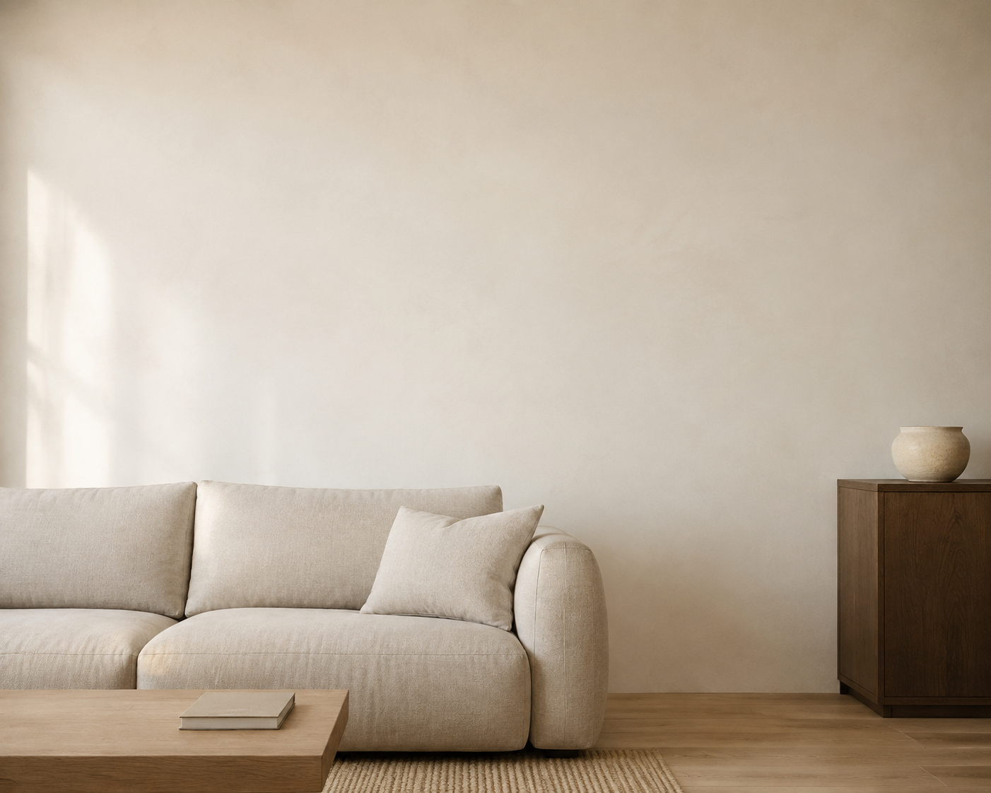 Een lichte woonkamer met een beige bank en een lege wand.