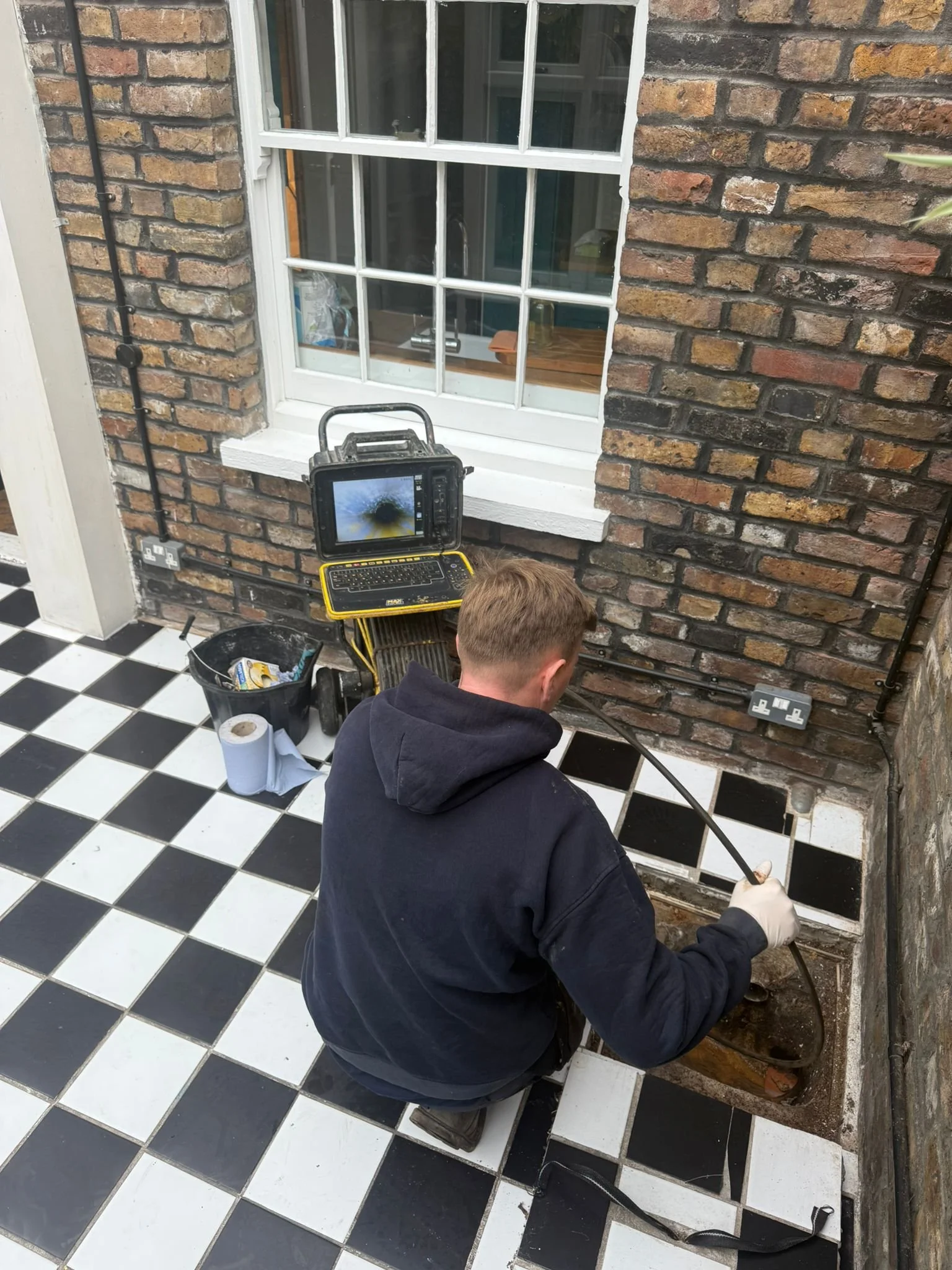 A person using CCTV drainage equipment to conduct a drain survey in London.