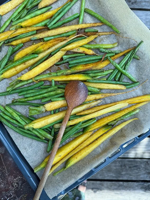 Bunte gelbe und grüne Frühlingszwiebeln auf Backpapier in einer Blechschale, mit Holzlöffel