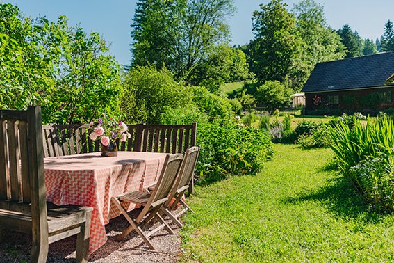 Gartentisch mit Blumen auf einem sonnigen, grünen Garten