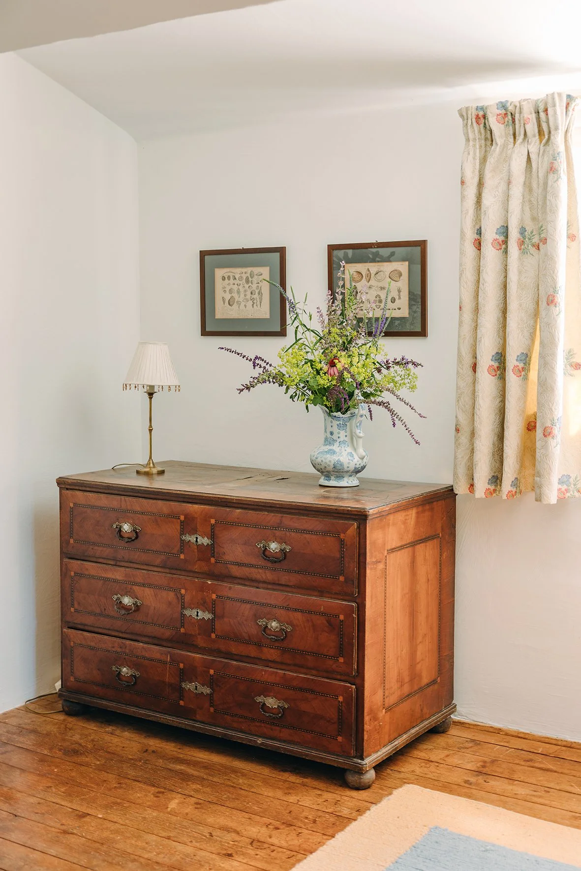 Vintage Kommode mit Blumenstrauß und Tischlampe in einem hellen Wohnzimmer