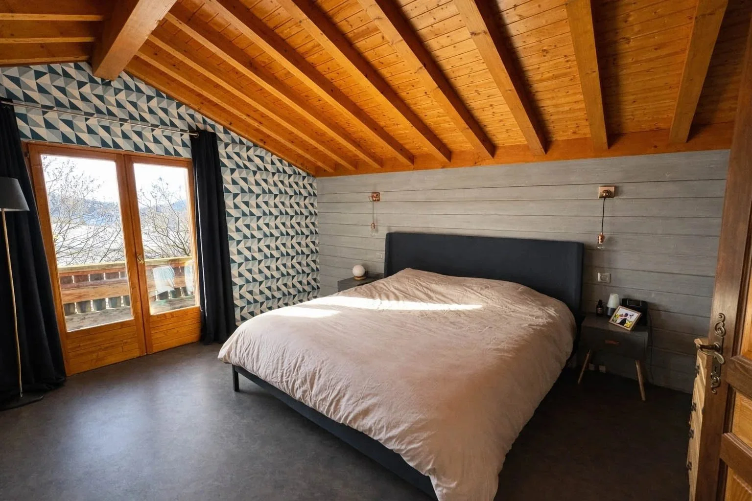 Vue d’une chambre en bois éclairée naturellement dans un chalet rénové, design montagne modernisé et harmonieux.