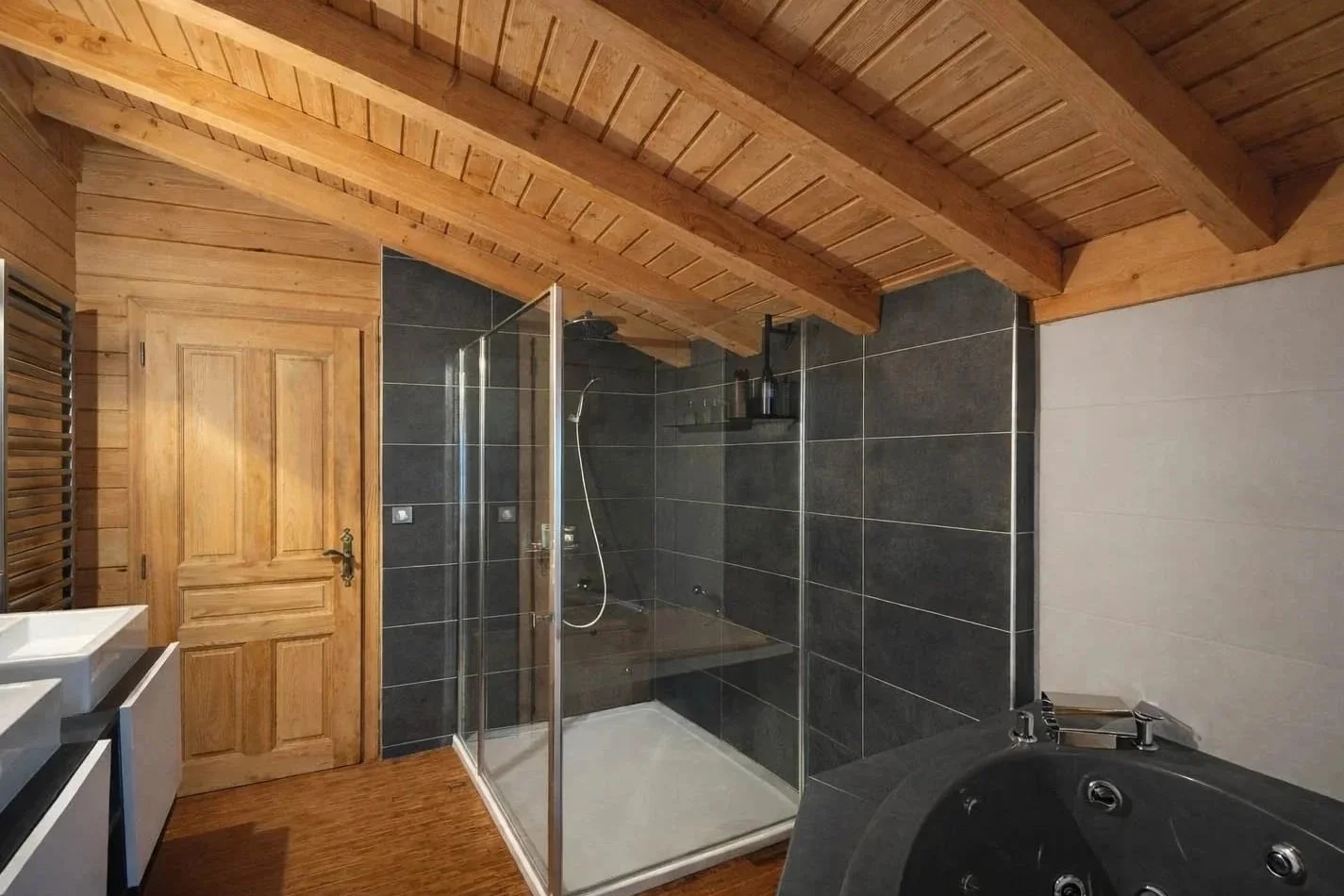 Détail de la salle de bain après rénovation, soulignant le bois brut du chalet contemporain.