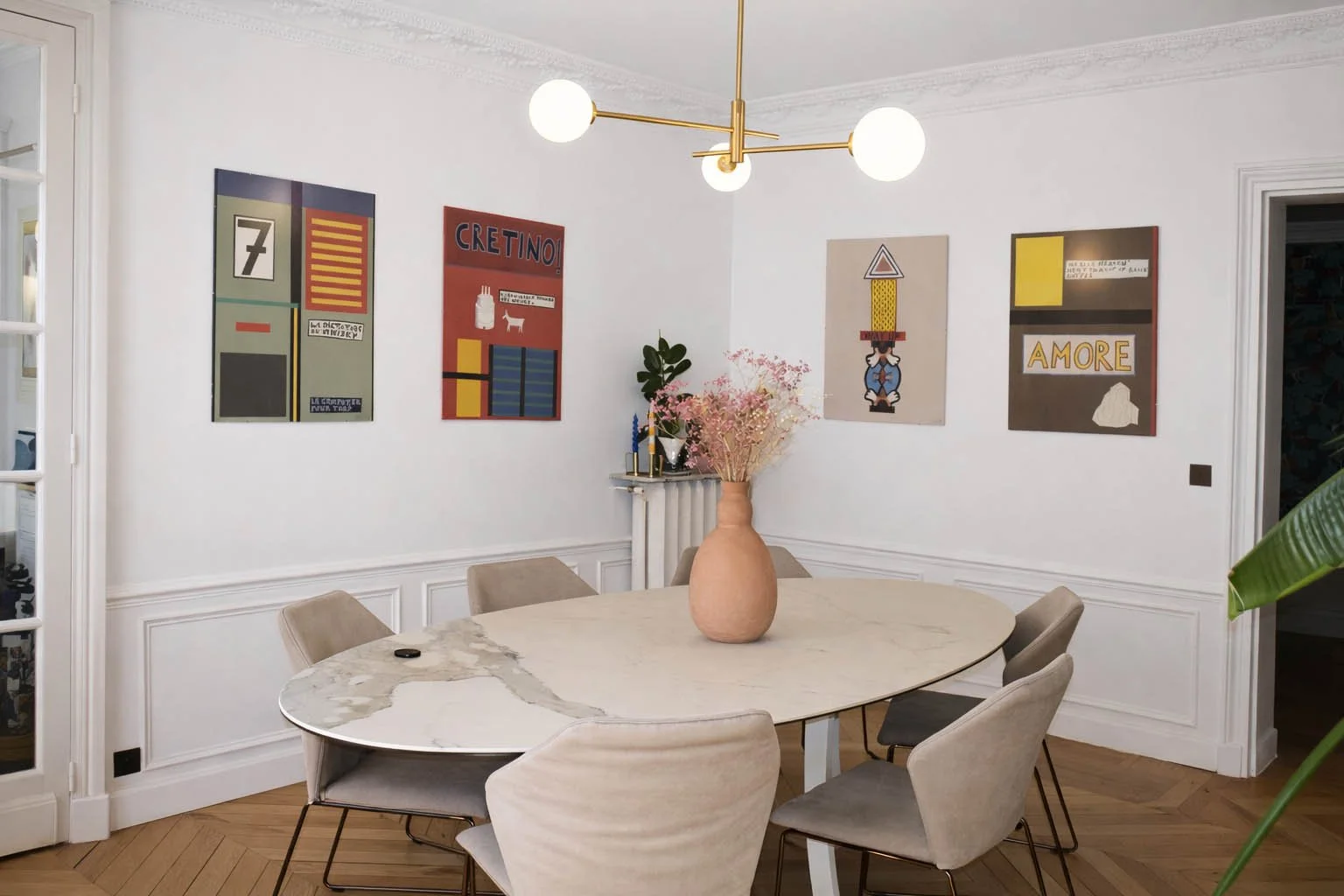 Dialogue entre architecture haussmannienne et mobilier contemporain dans une salle à manger parisienne rénovée.