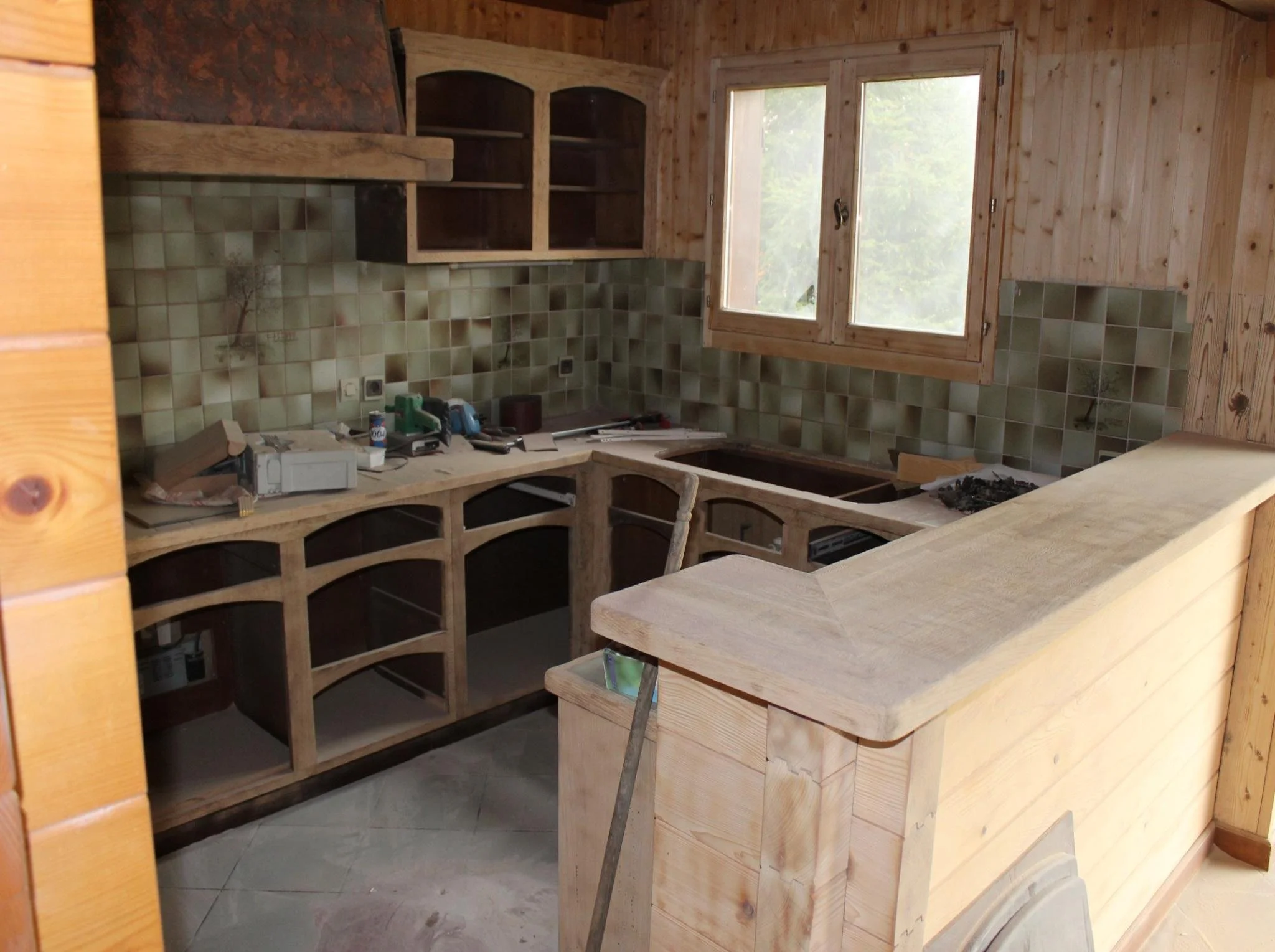 Travail des matériaux dans une cuisine de chalet rénovée, bois brossé et surfaces contemporaines en lumière.