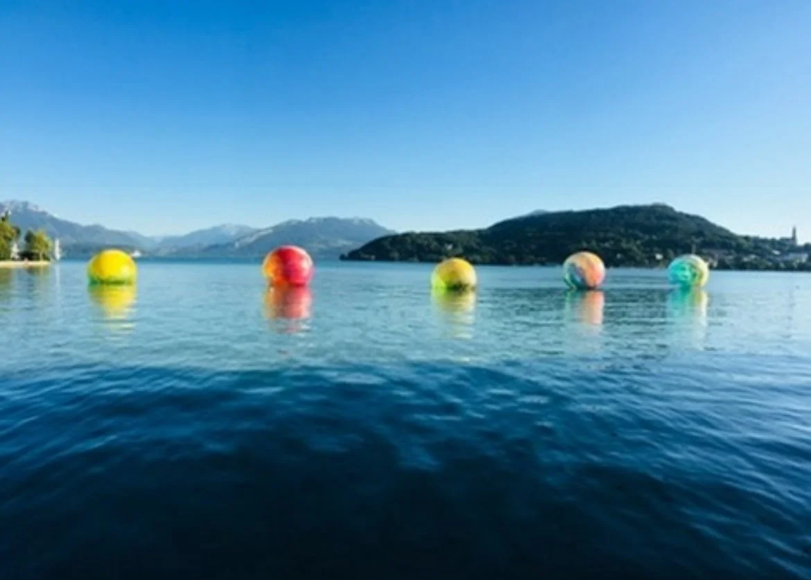 Colourful floating balls on Lake Annecy with mountains in the background