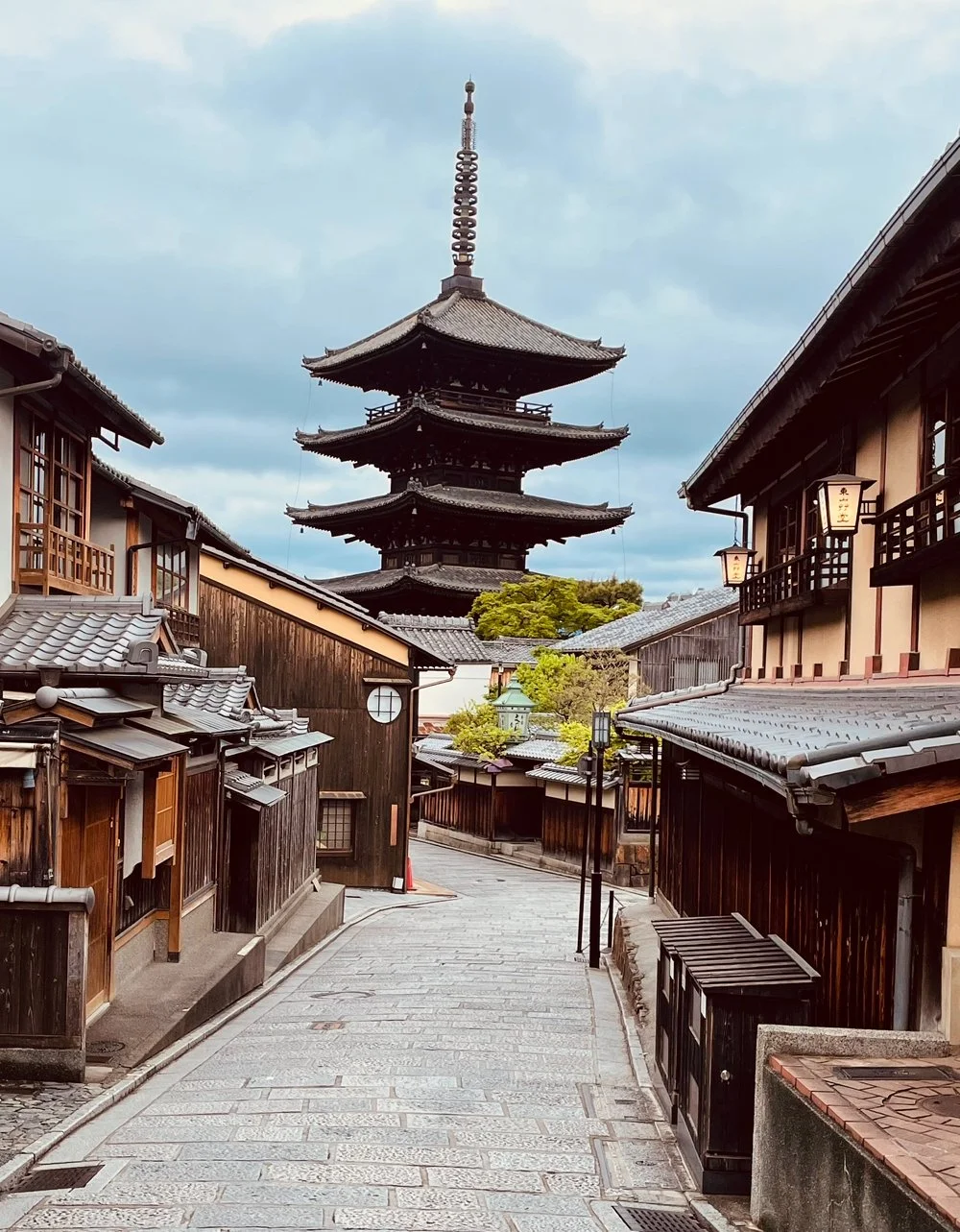 Traditional Japanese street with wooden buildings and a pagoda in the background.