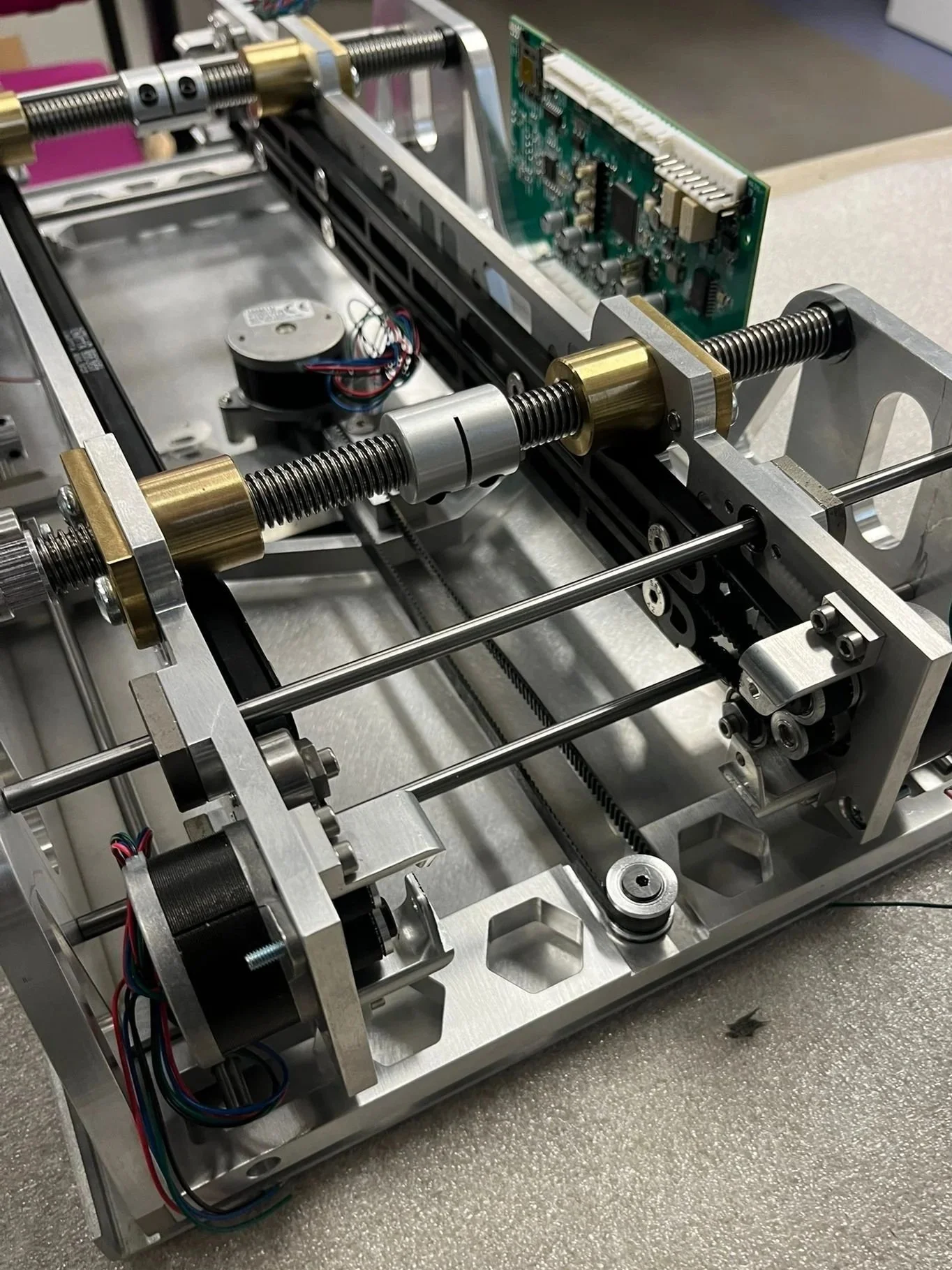 A close-up of a mechanical assembly with metal rods, screws, and electronic components, possibly part of a precision machine or robotics system.