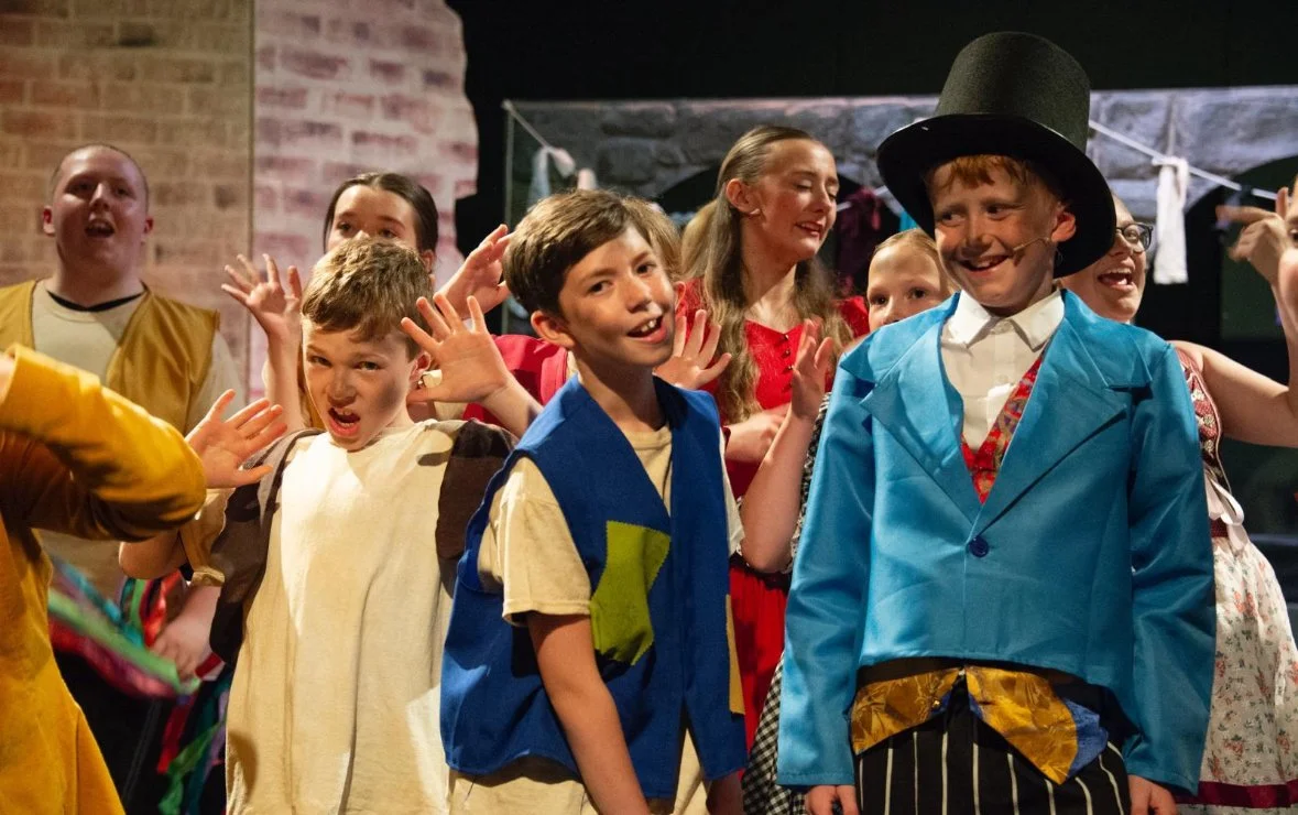 Children dressed in costumes performing on stage during a play.