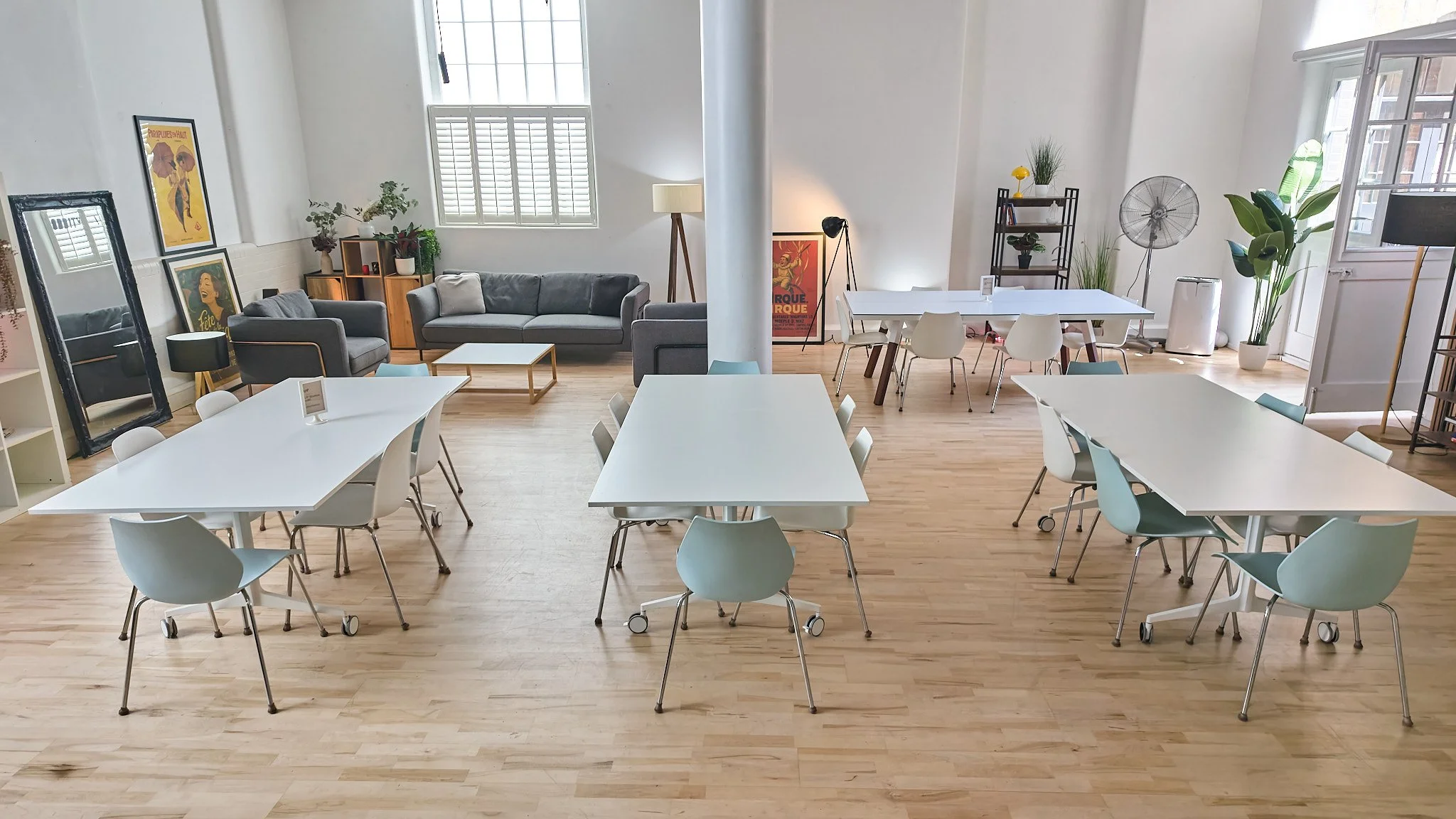 Bright workshop layout – Flexible table seating beneath high ceilings and skylights, with cosy lounge seating alongside.