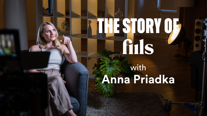 A woman sitting on a gray sofa in a studio, being interviewed with professional lighting and camera equipment, with the text 'The story of films with Anna Priadka' overlaid.
