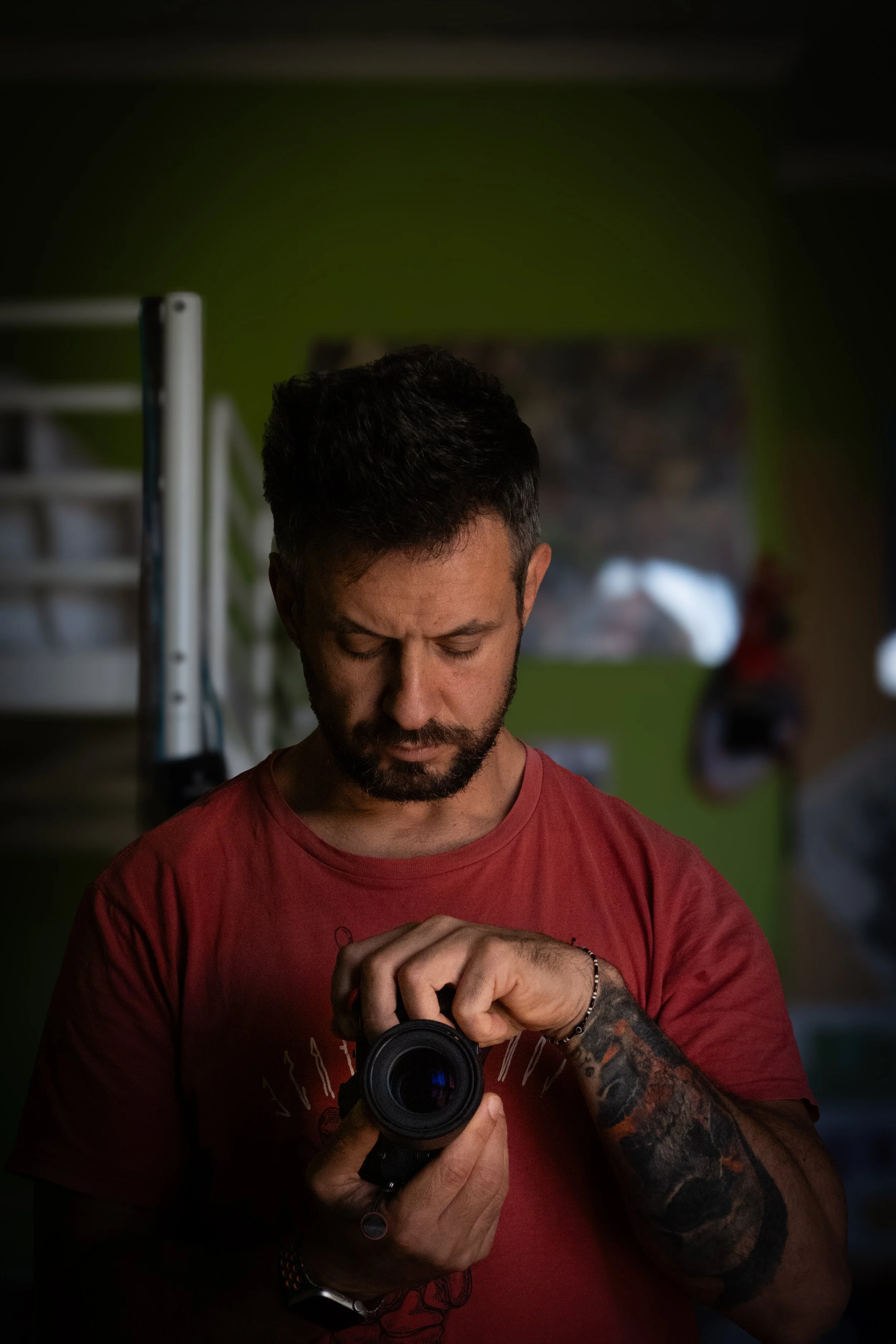 Uomo con tatuaggi che si guarda nello specchio mentre tiene una macchina fotografica