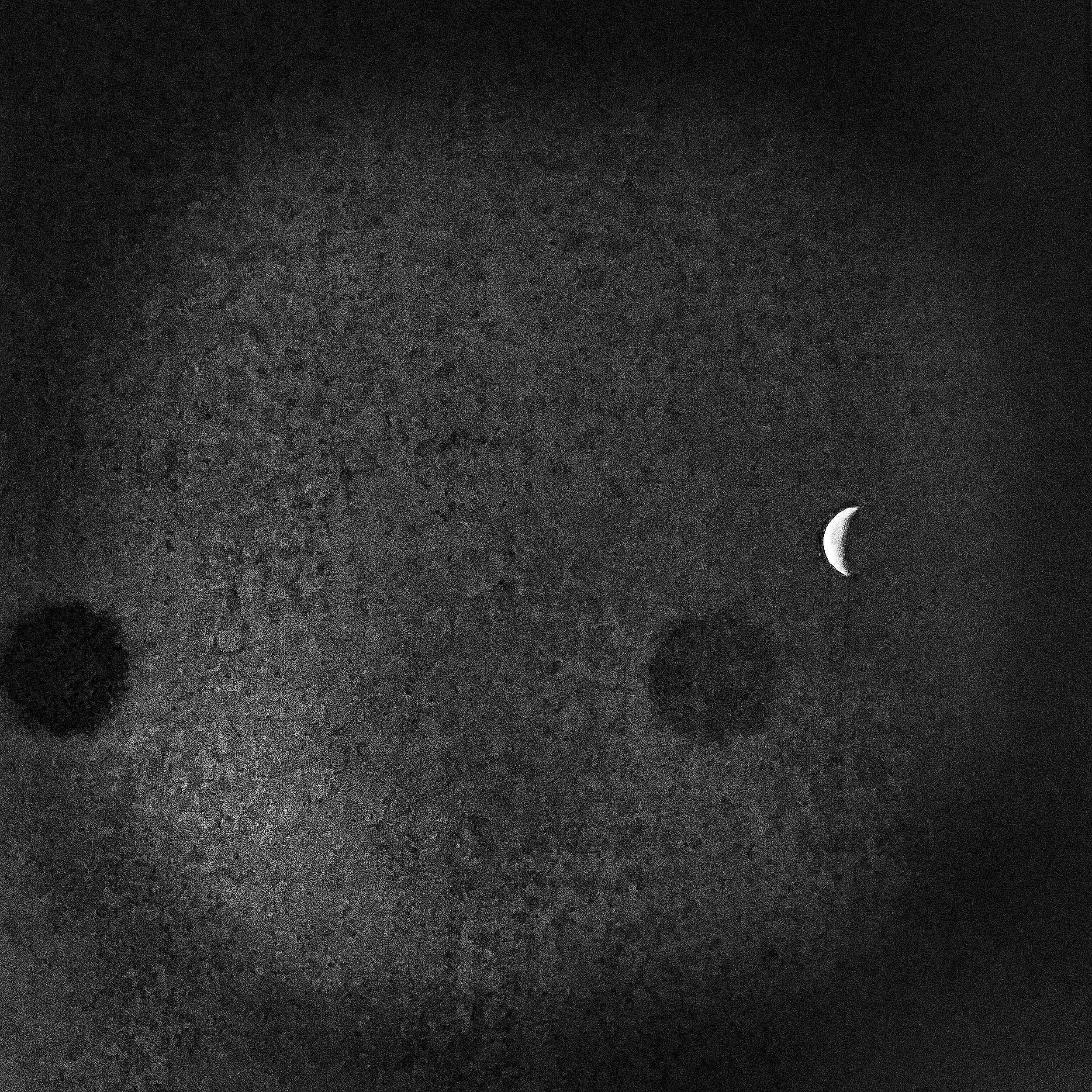 A crescent moon in the night sky with clouds and a starry background.