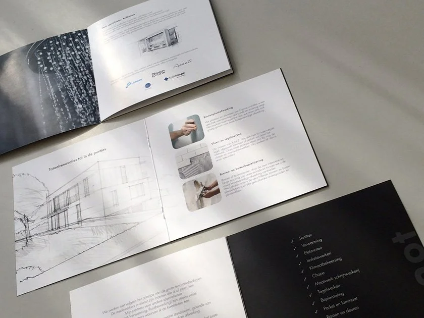 Open and closed booklets with technical illustrations and informational text on a light-colored surface.