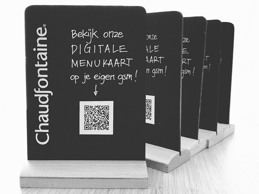 Set of black chalkboard menu cards on a wooden stand, advertising digital menu cards with a QR code in Dutch.