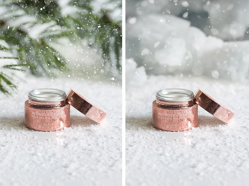 A pink jar labeled 'Wonder Cream Skin Drink Moisturizer' with its lid off, on a snowy surface with snow falling around it. The background features evergreen branches and a snowy landscape.