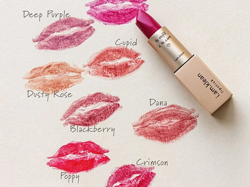 Swatches of various lipstick shades with handwritten labels and a lipstick tube with a fuchsia shade.