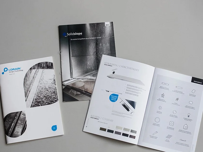 Open brochures and a booklet about building or construction materials on a gray surface.
