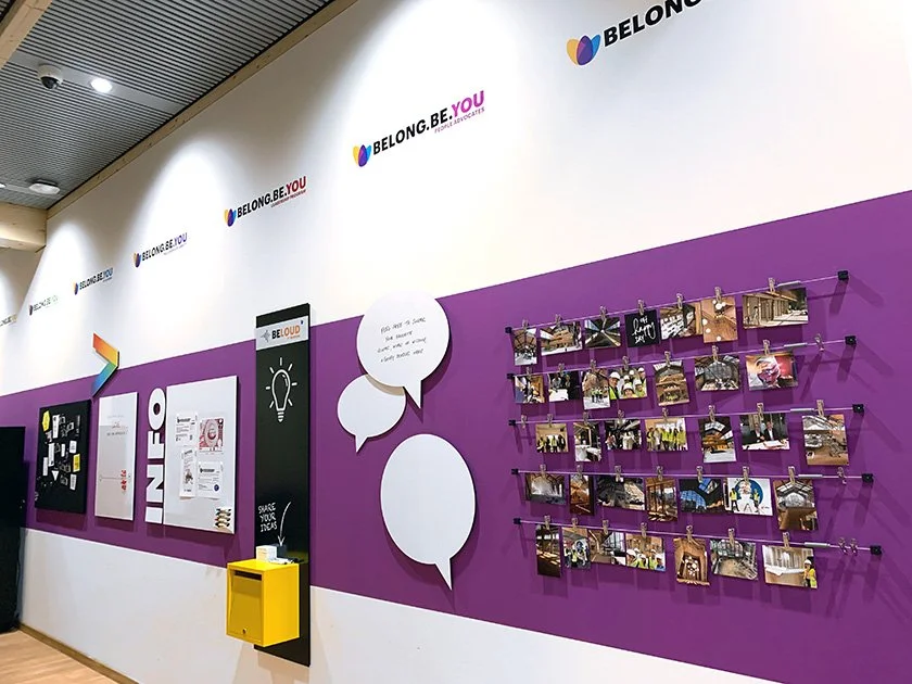 Gallery wall with photos, speech bubbles, and informational displays at an event or conference.