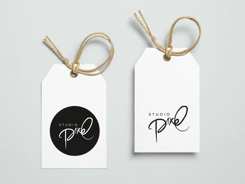 Two white tags with natural twine strings, one with a black circle logo and the other with black handwritten text reading 'Studio Piko'.