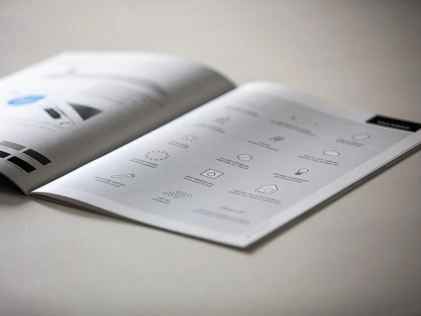 Open booklet or magazine on a white surface showing diagrams and icons related to design or instruction.