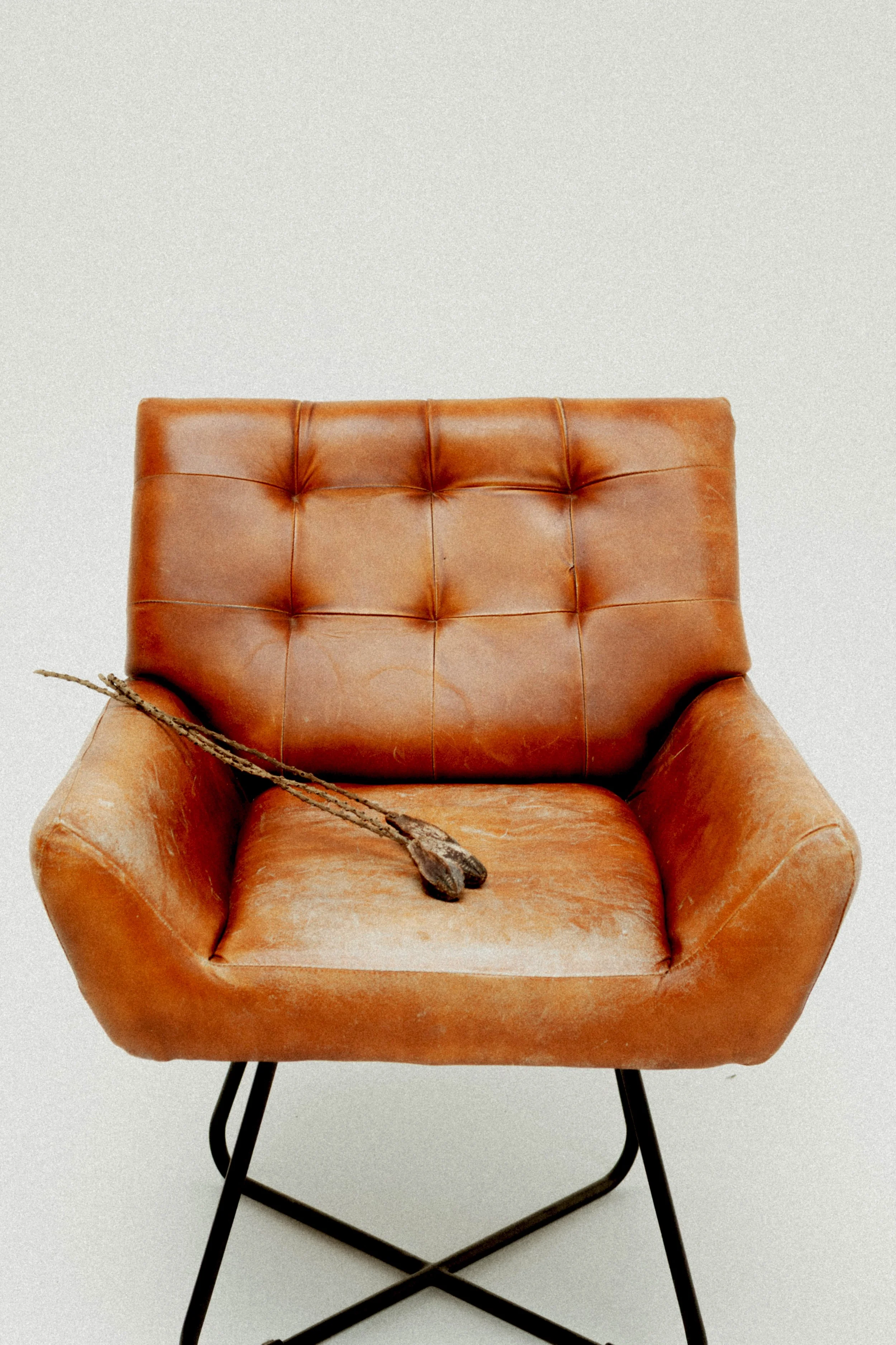 An old, worn orange leather chair with a rustic wooden spoon resting on the seat.