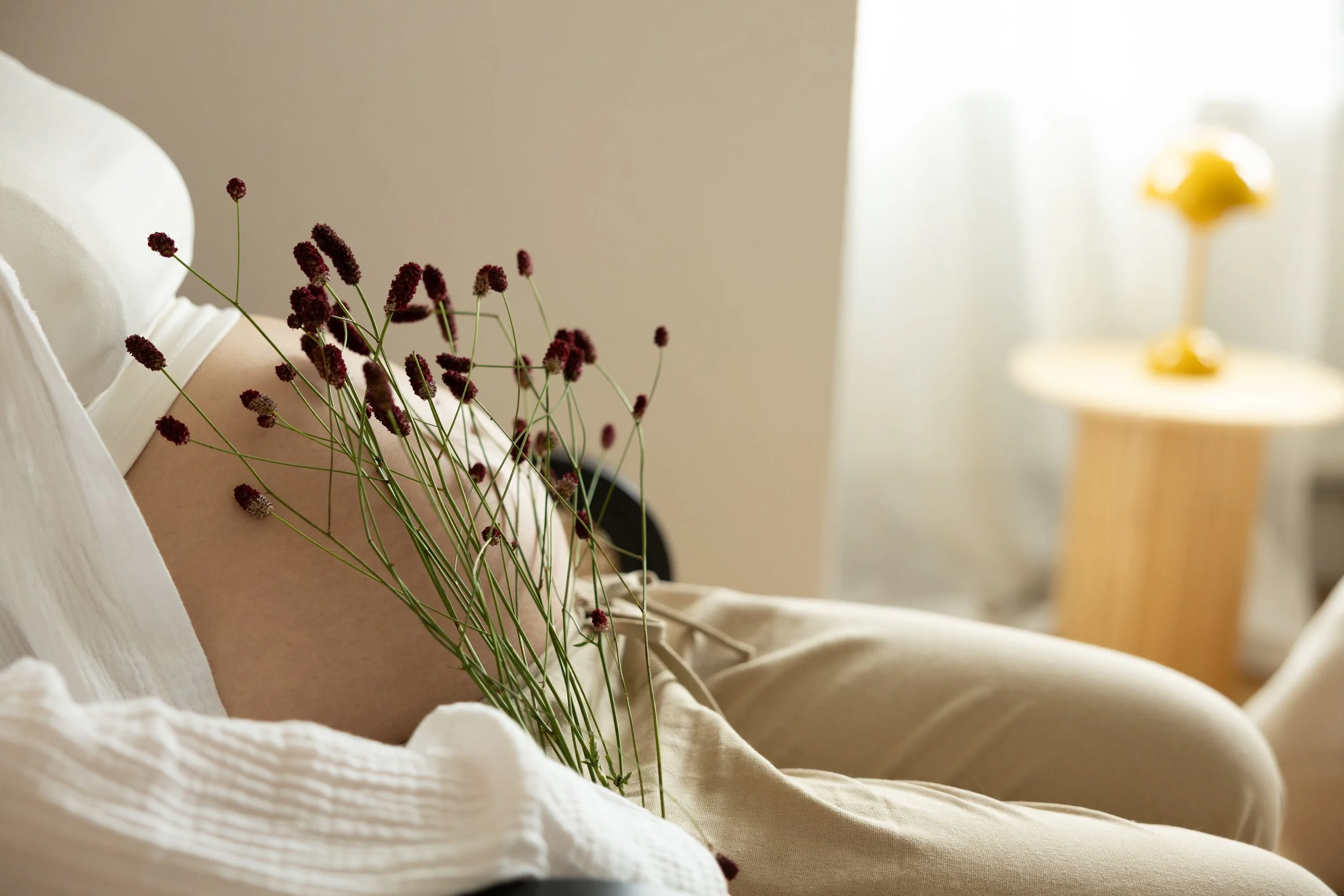 Werdende Mutter während eines natürlichen Babybauchshootings in Hannover mit floralen Details und warmer Lichtstimmung.