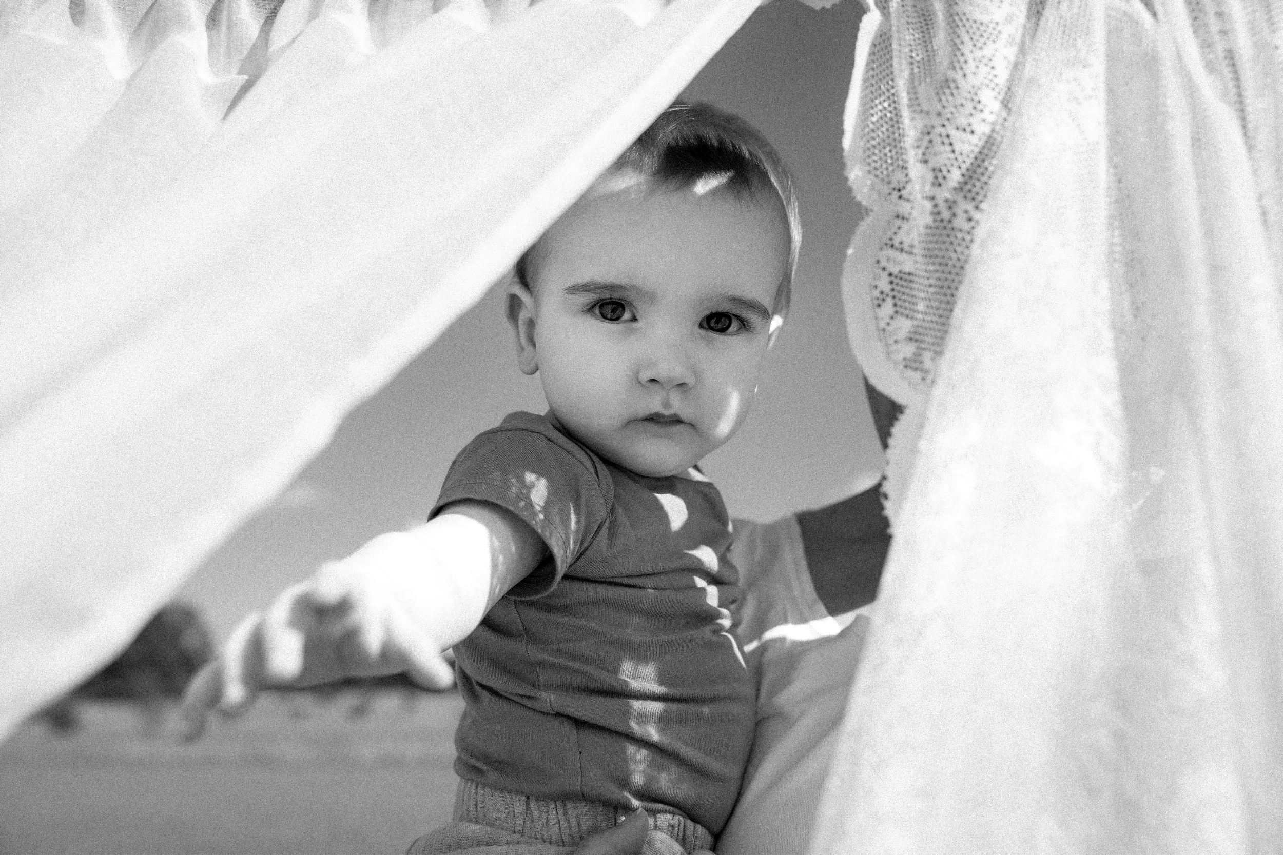 Verträumter Blick vom Baby durch Gardinen