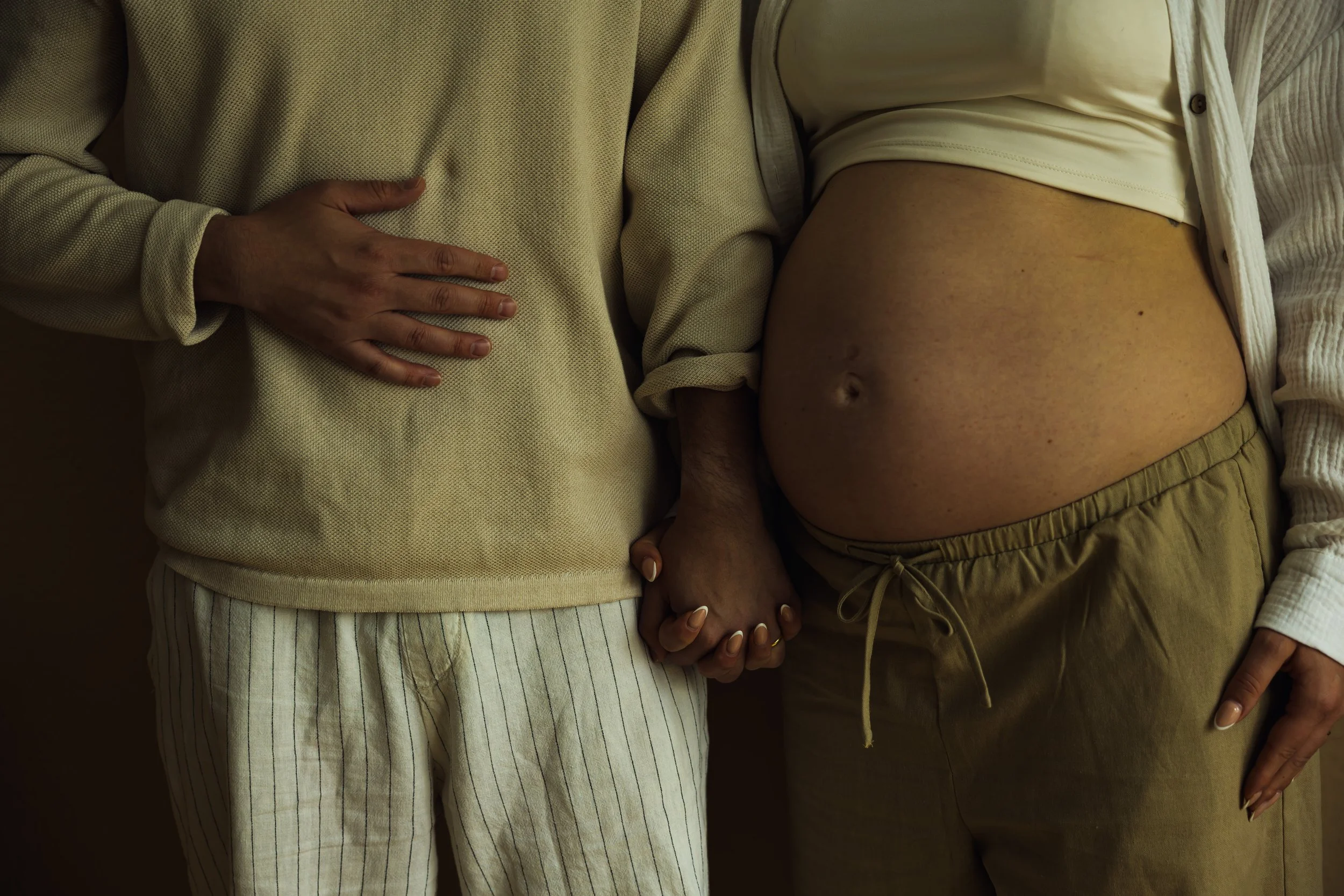 Werdende Eltern halten während eines natürlichen Babybauchshootings in Hannover ihre Hände auf dem Babybauch.